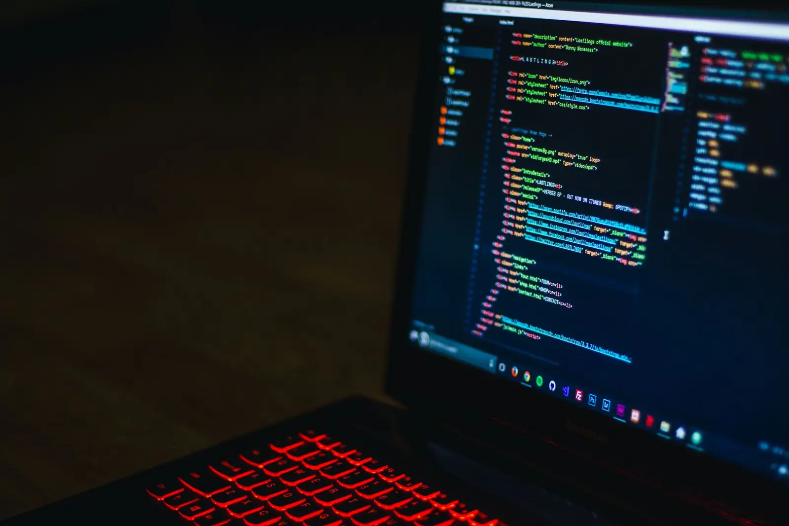 Laptop with red backlit keyboard showing code on screen in dark mode