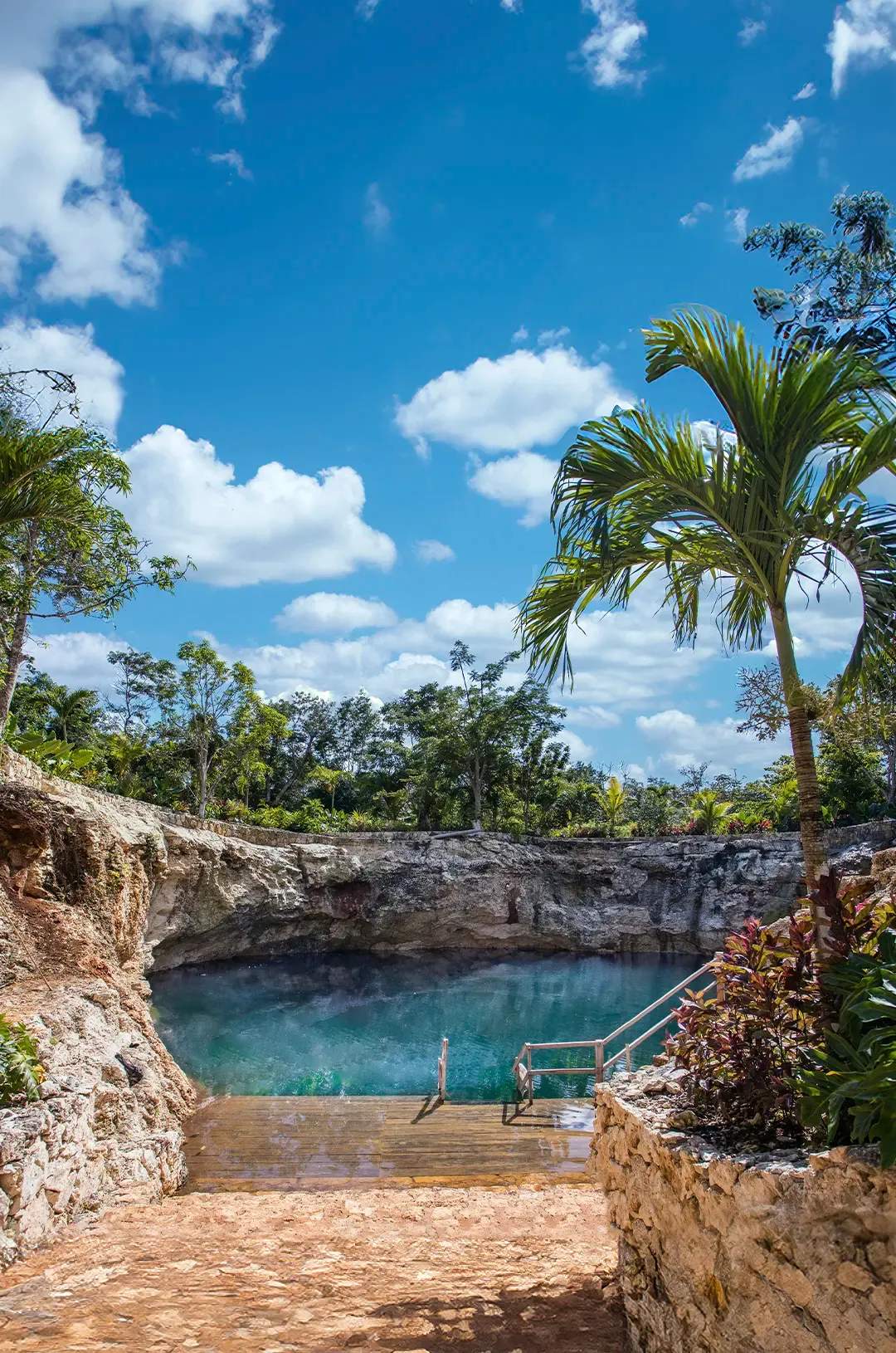 Hermoso cenote de agua azul clara rodeado de acantilados rocosos