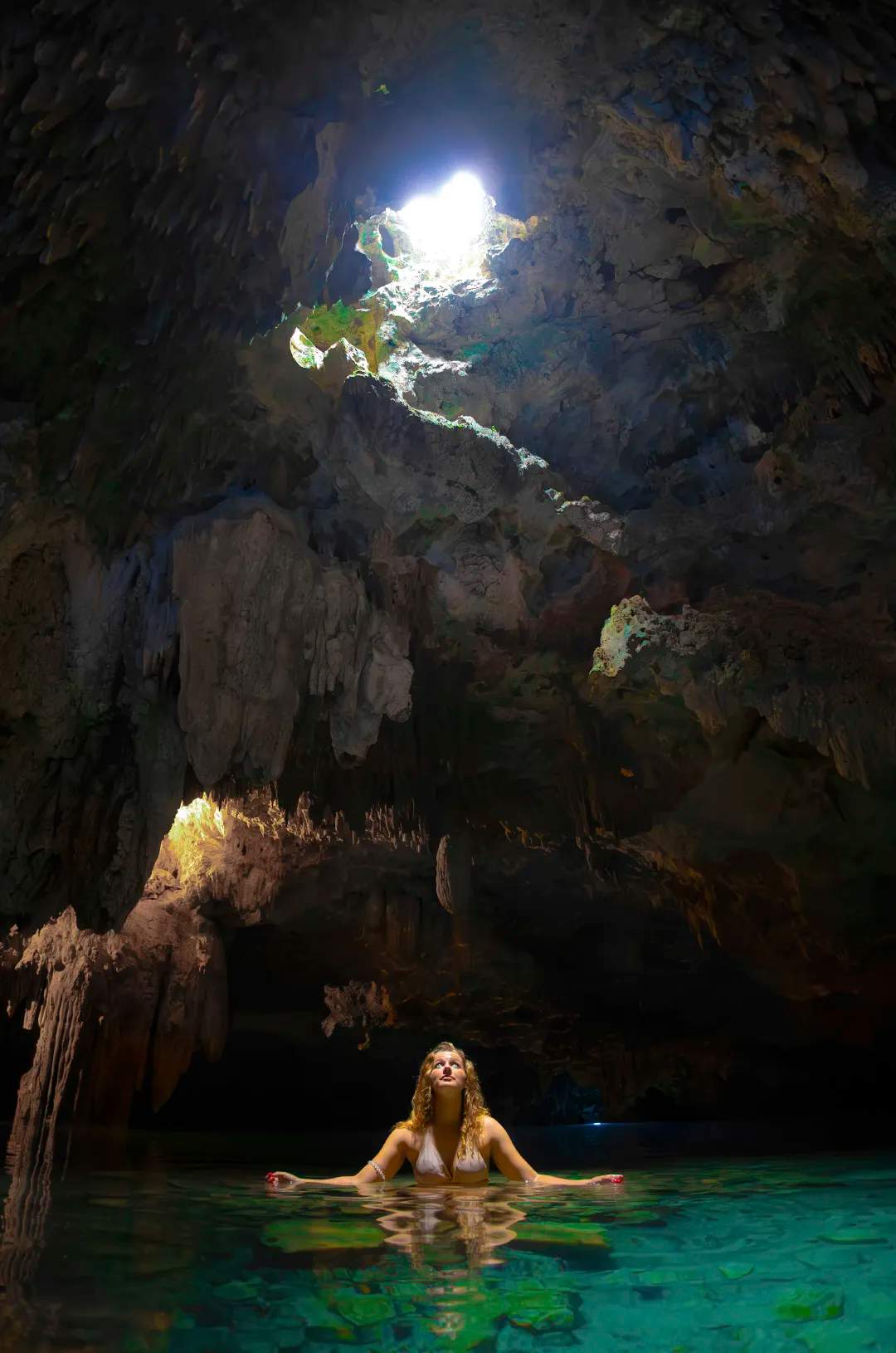 Mujer disfrutando de un baño sereno en una impresionante cueva de cenote