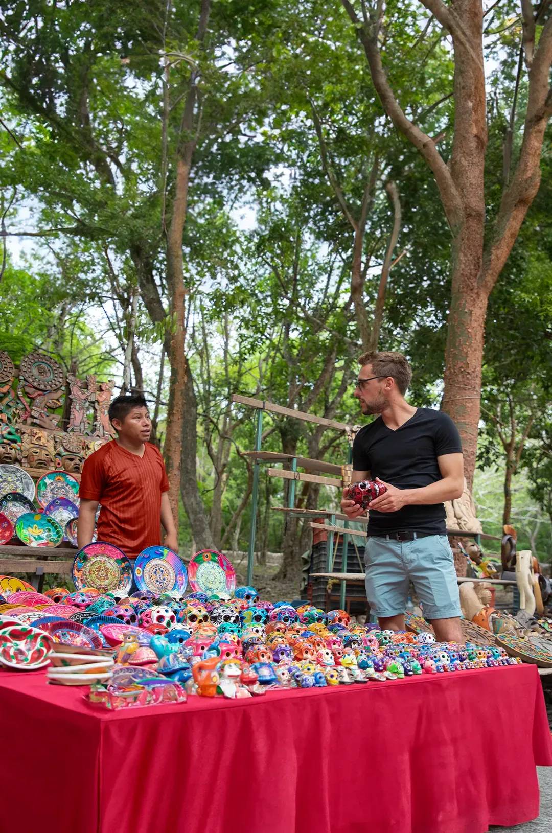 Turista comprando coloridas artesanías a un vendedor en Chichen Itzá.