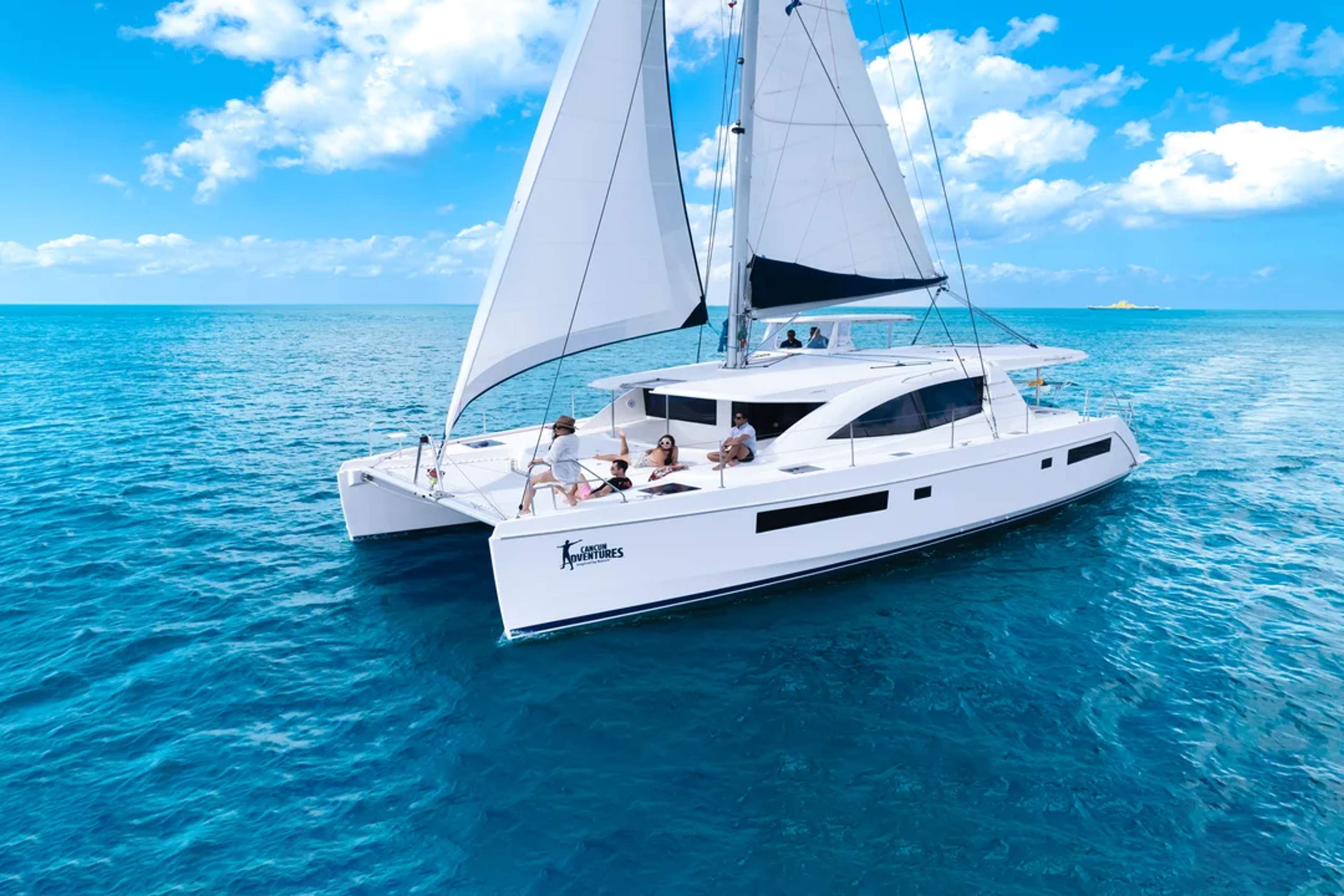 Catamarán elegante navegando en aguas turquesa bajo un cielo azul con huéspedes felices.
