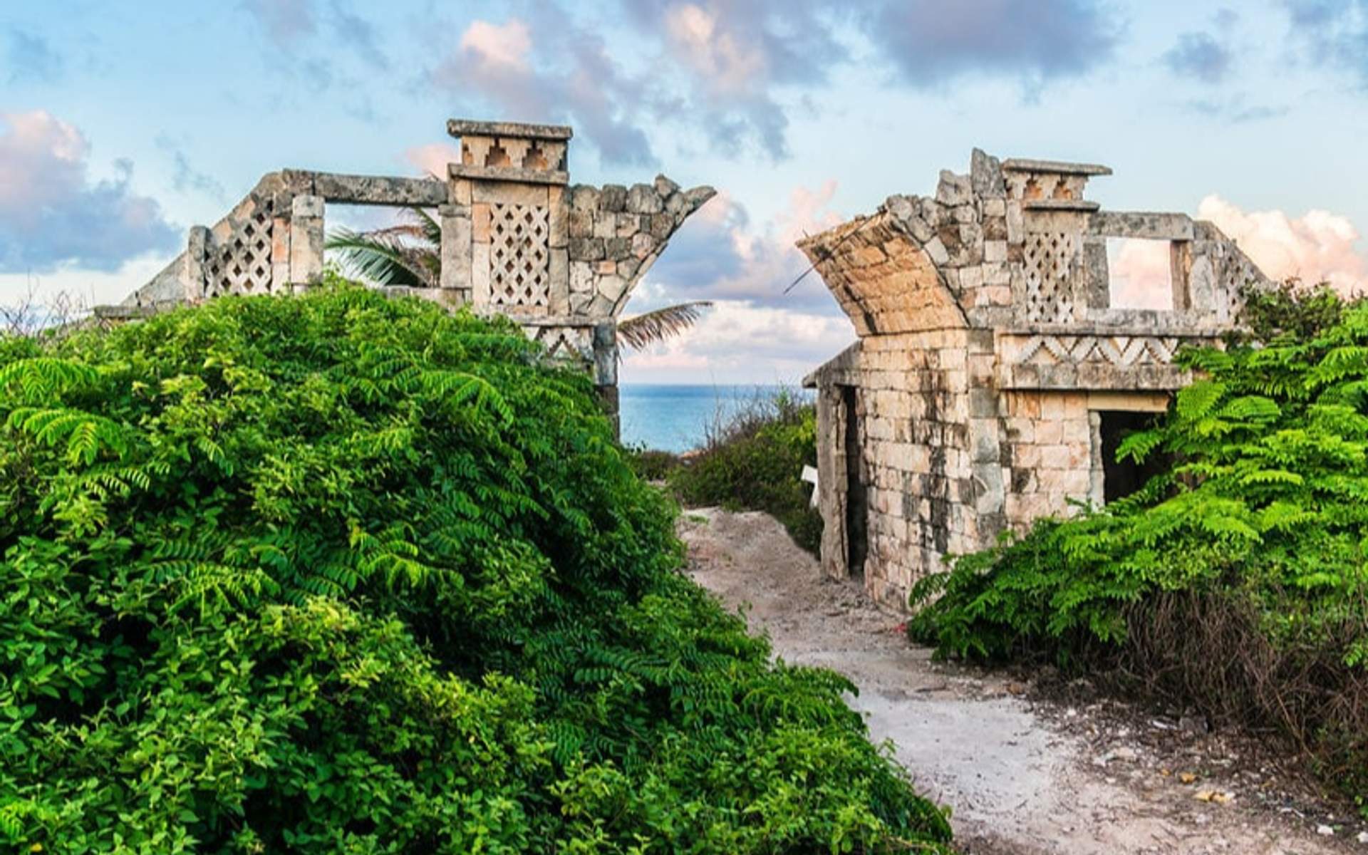 Ruins of the temple of the goddess Ixchel on Isla Mujeres, surrounded by lush greenery and offering a view of the ocean.
