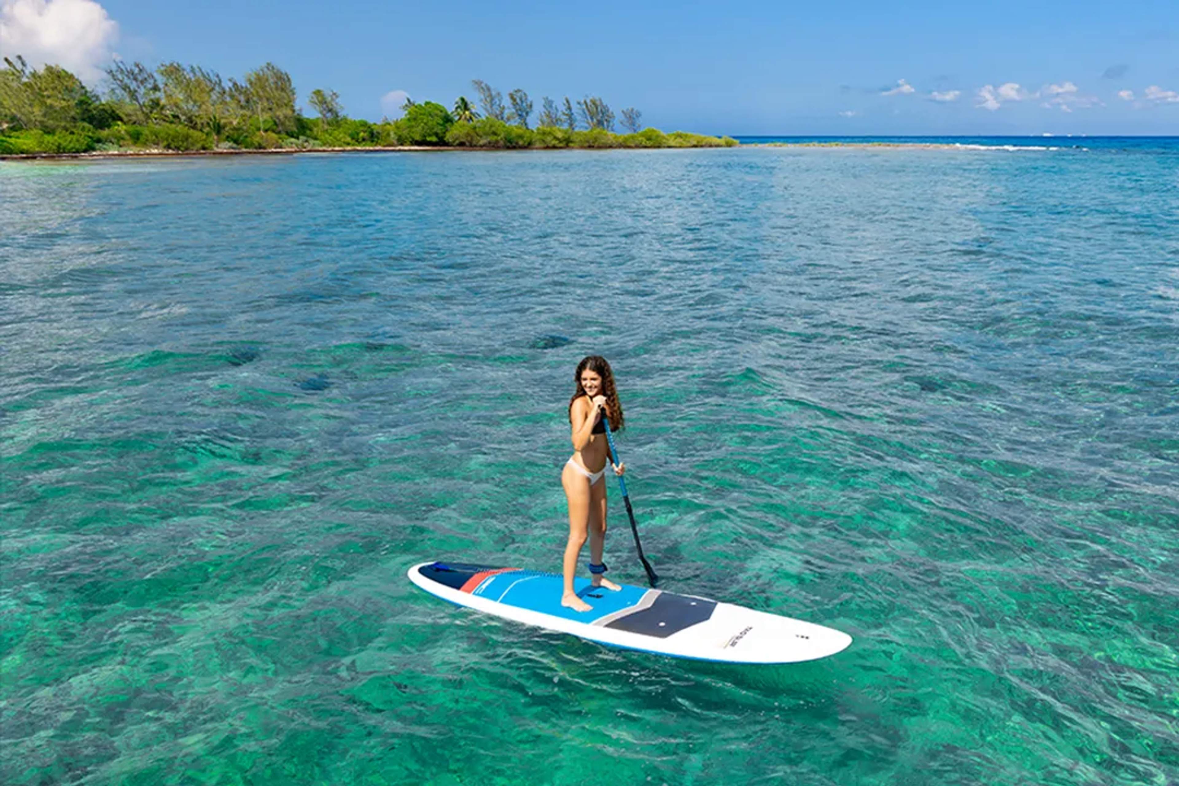 Mujer practicando paddleboard en aguas turquesa del Caribe en tour de catamarán Riviera Maya