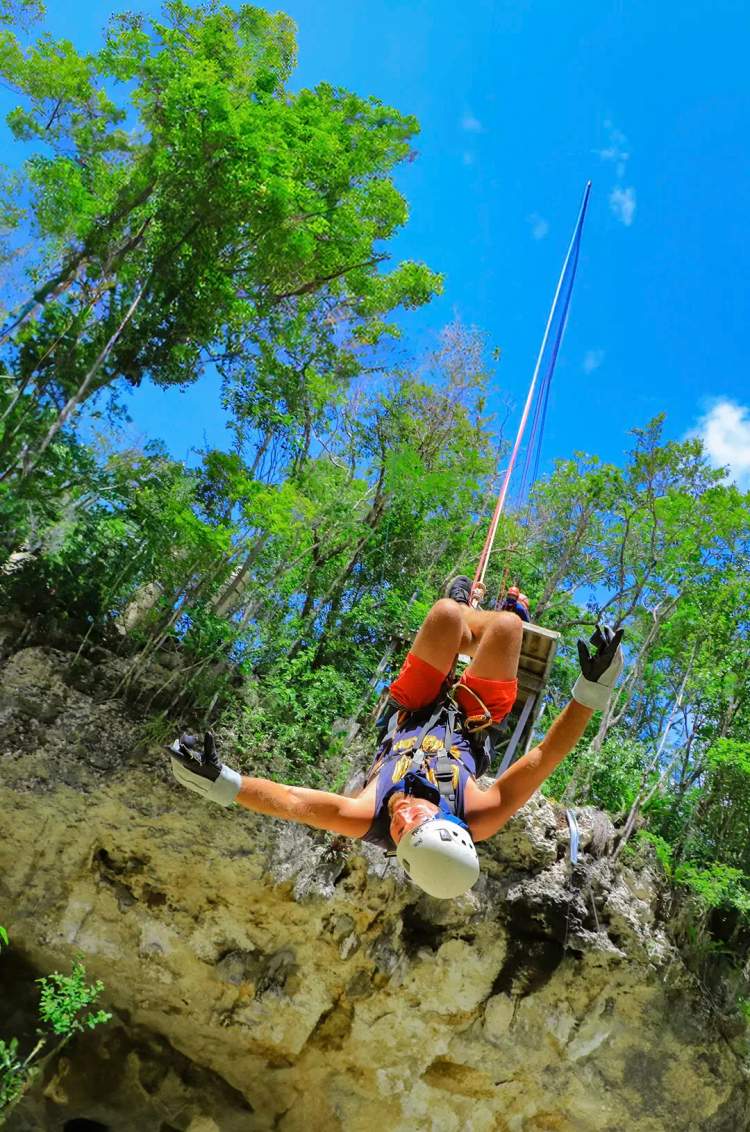 Persona en tirolesa, colgando boca abajo en una emocionante aventura outdoor en Cancún.