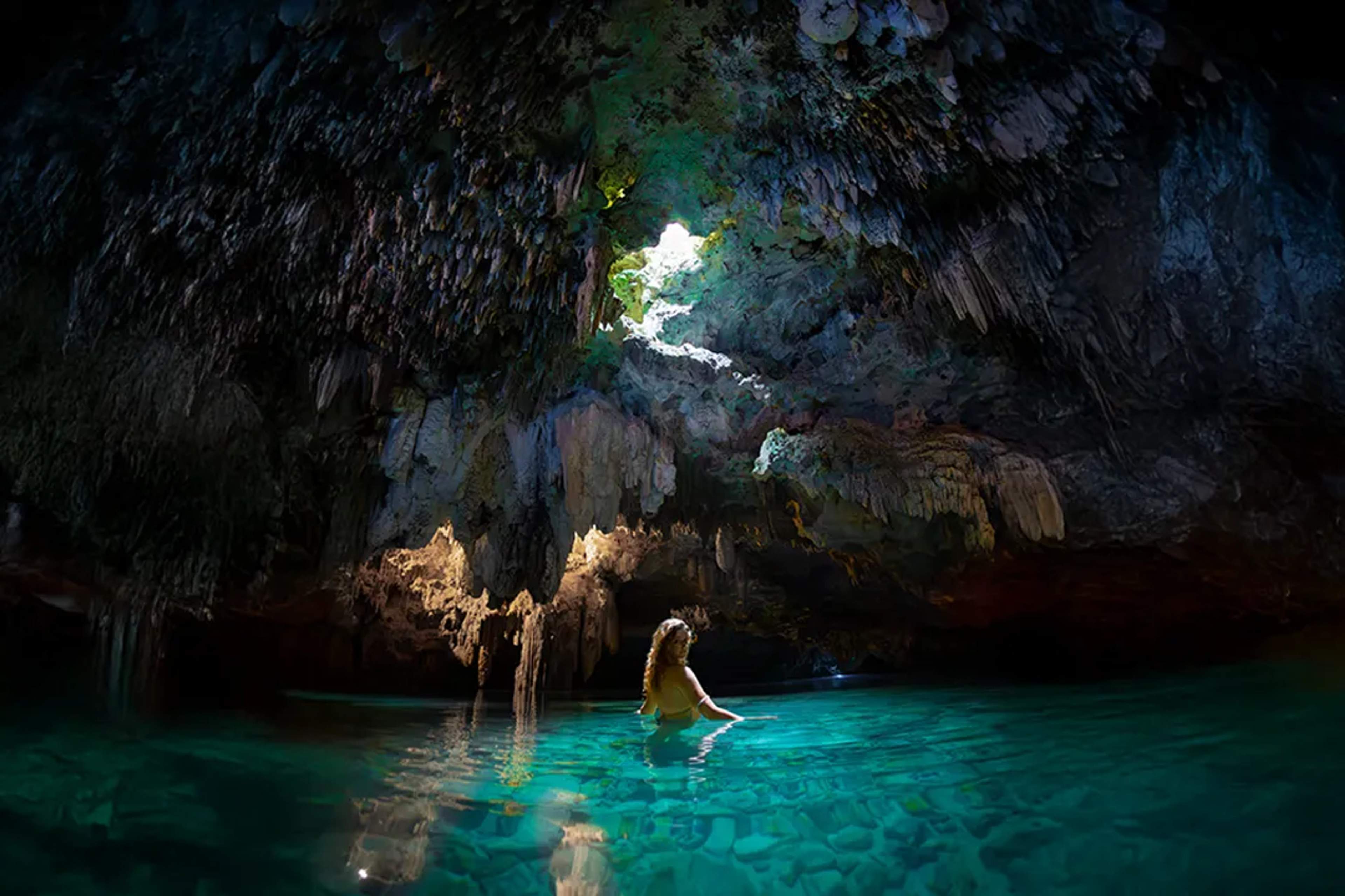 Woman swimming in a crystal-clear cenote cave near Cancun on a guided Riviera Maya adventure tour