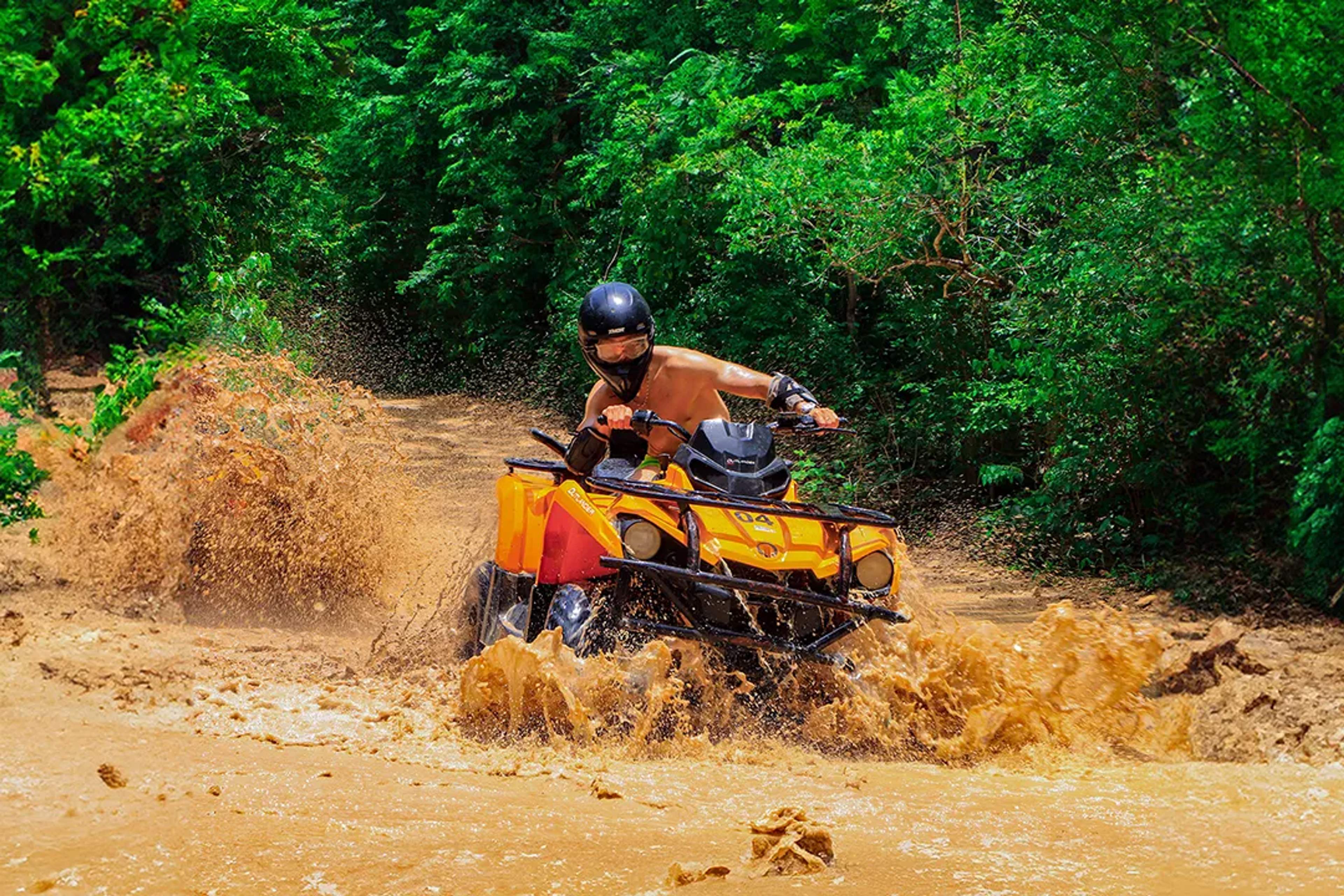 Conductor de ATV cruza lodo en un sendero selvático durante un emocionante tour de Cancun Adventures