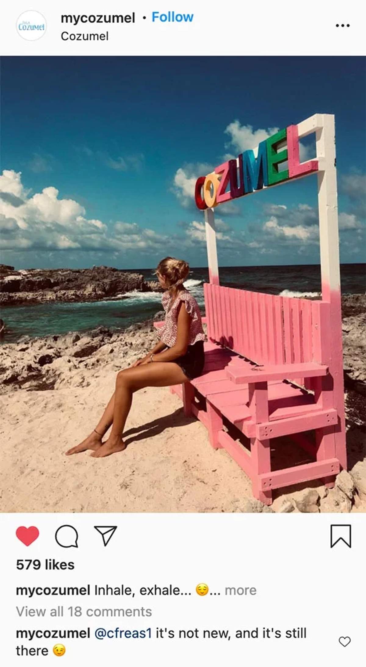 A woman sitting on a pink bench with the word "Cozumel" in colorful letters, enjoying the beach view.