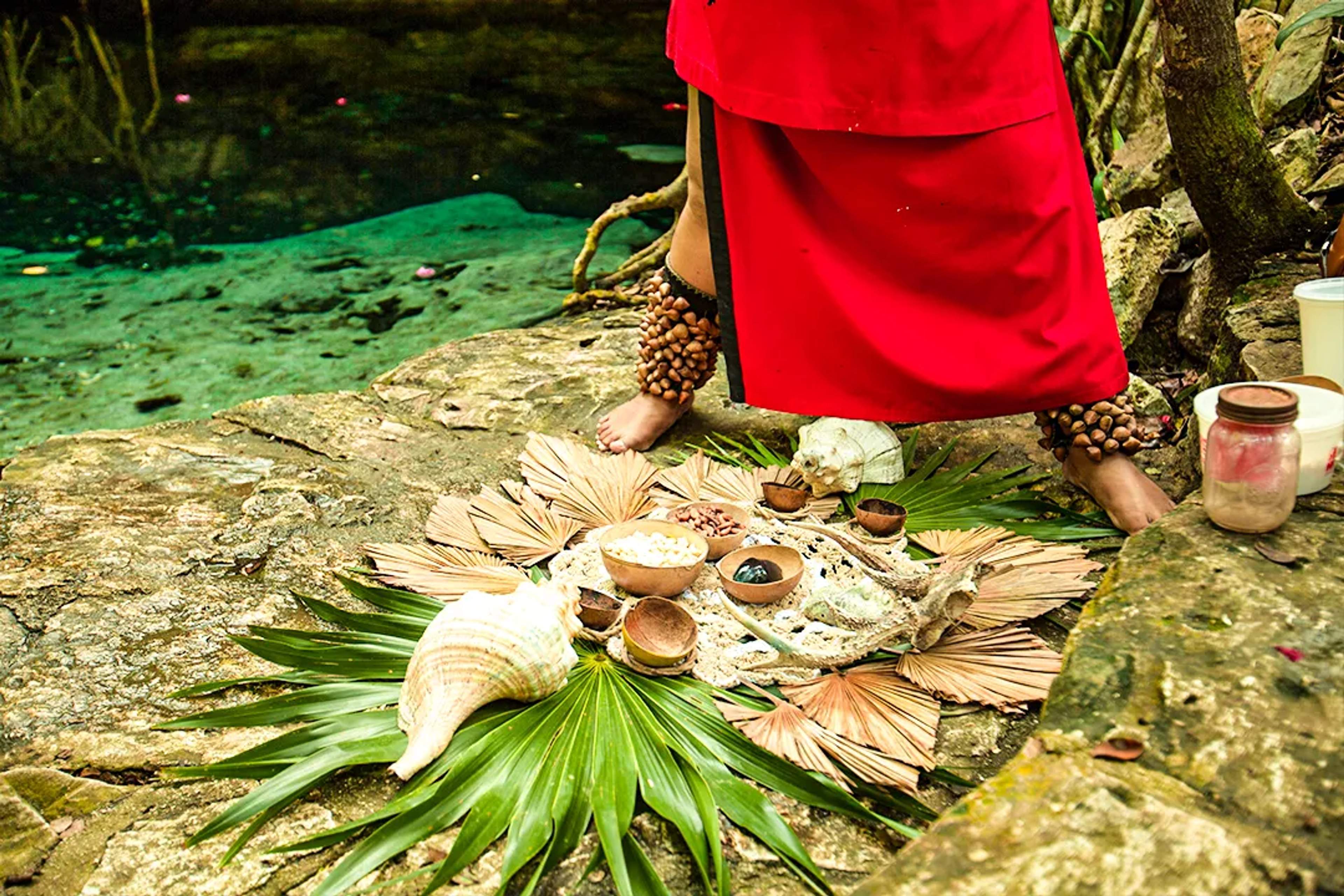 Ceremonia maya tradicional junto a un cenote, con ofrendas sagradas, hojas de palma y ritual ancestral
