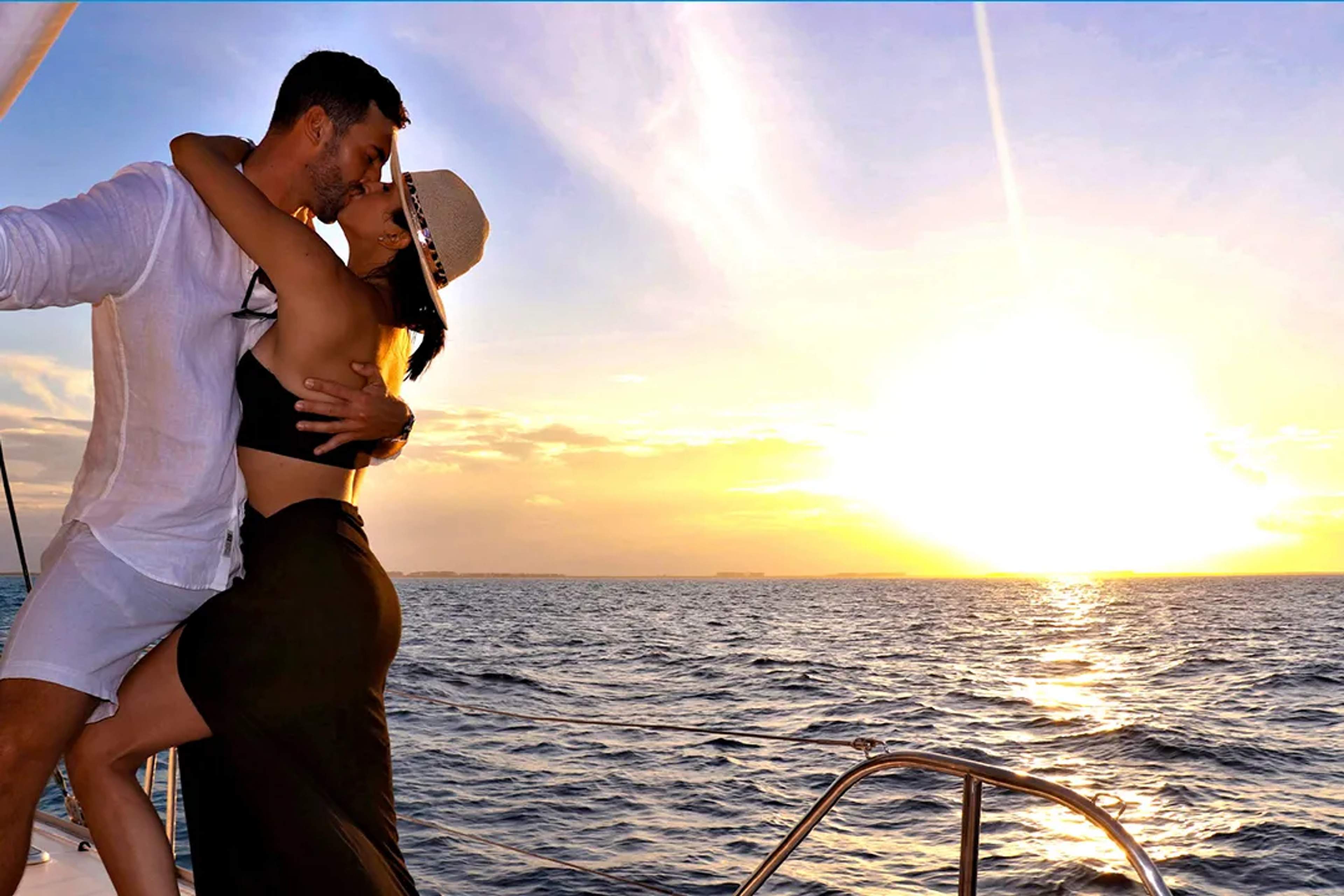 Couple sharing a romantic moment during a sunset sailing experience in Cancún, surrounded by ocean views and golden light