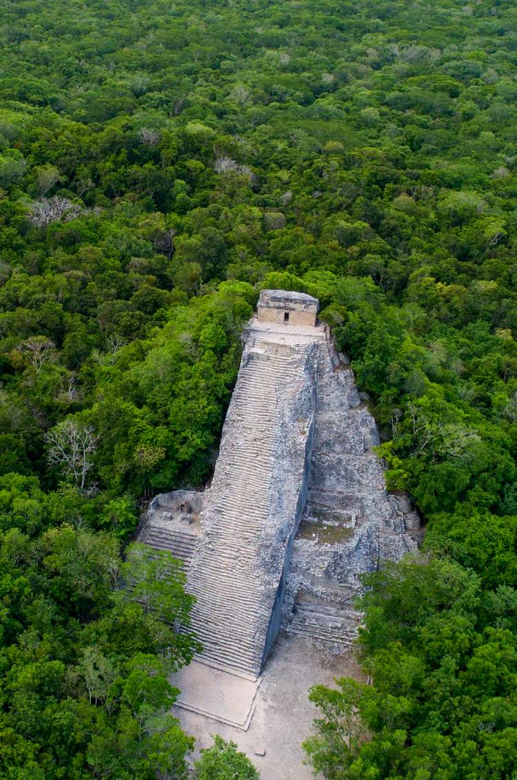 Coba ruins, aerial view of an ancient Mayan pyramid surrounded by dense green jungle.