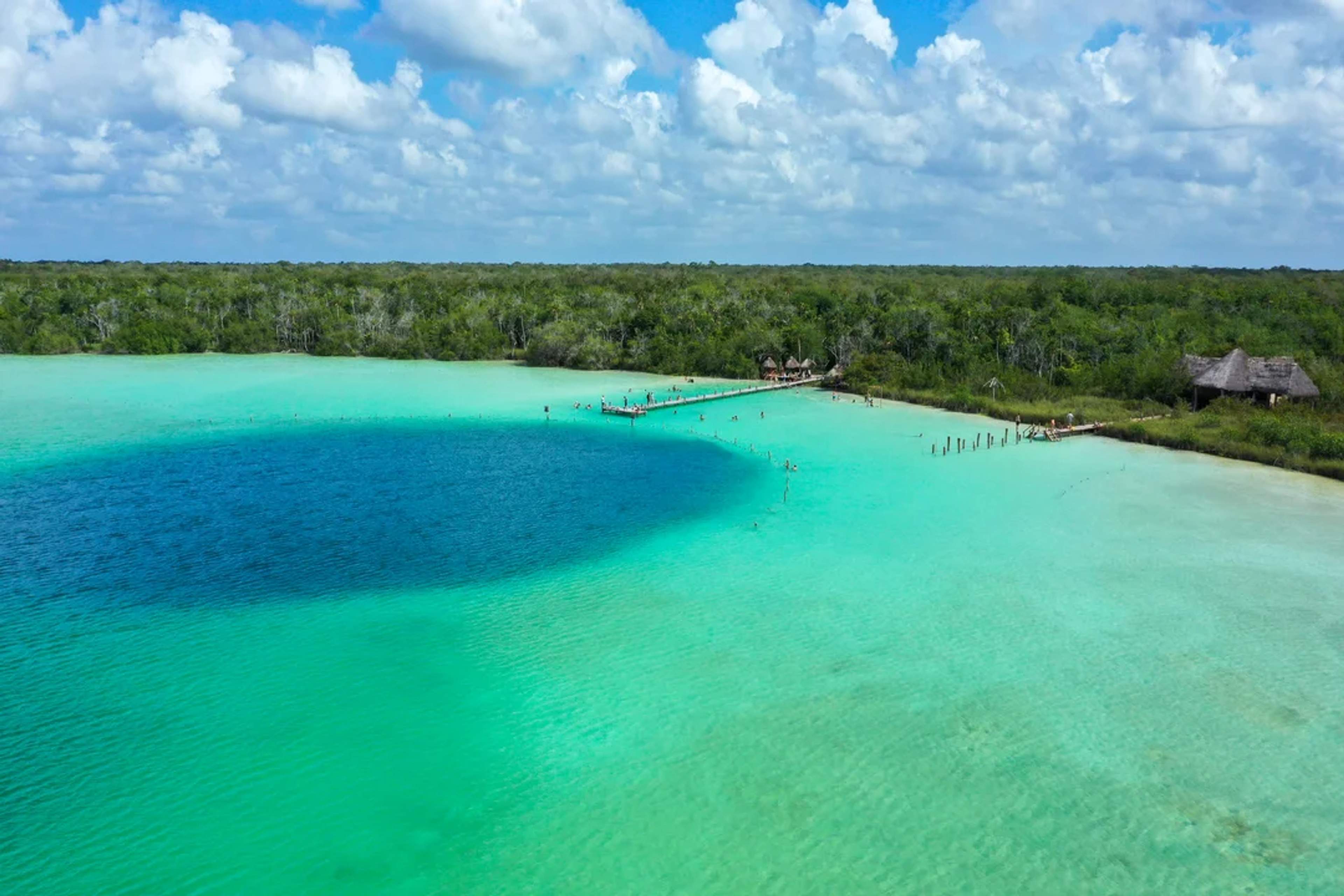 Kaan Luum Lagoon glows with turquoise and deep blue tones, surrounded by lush jungle near Tulum.