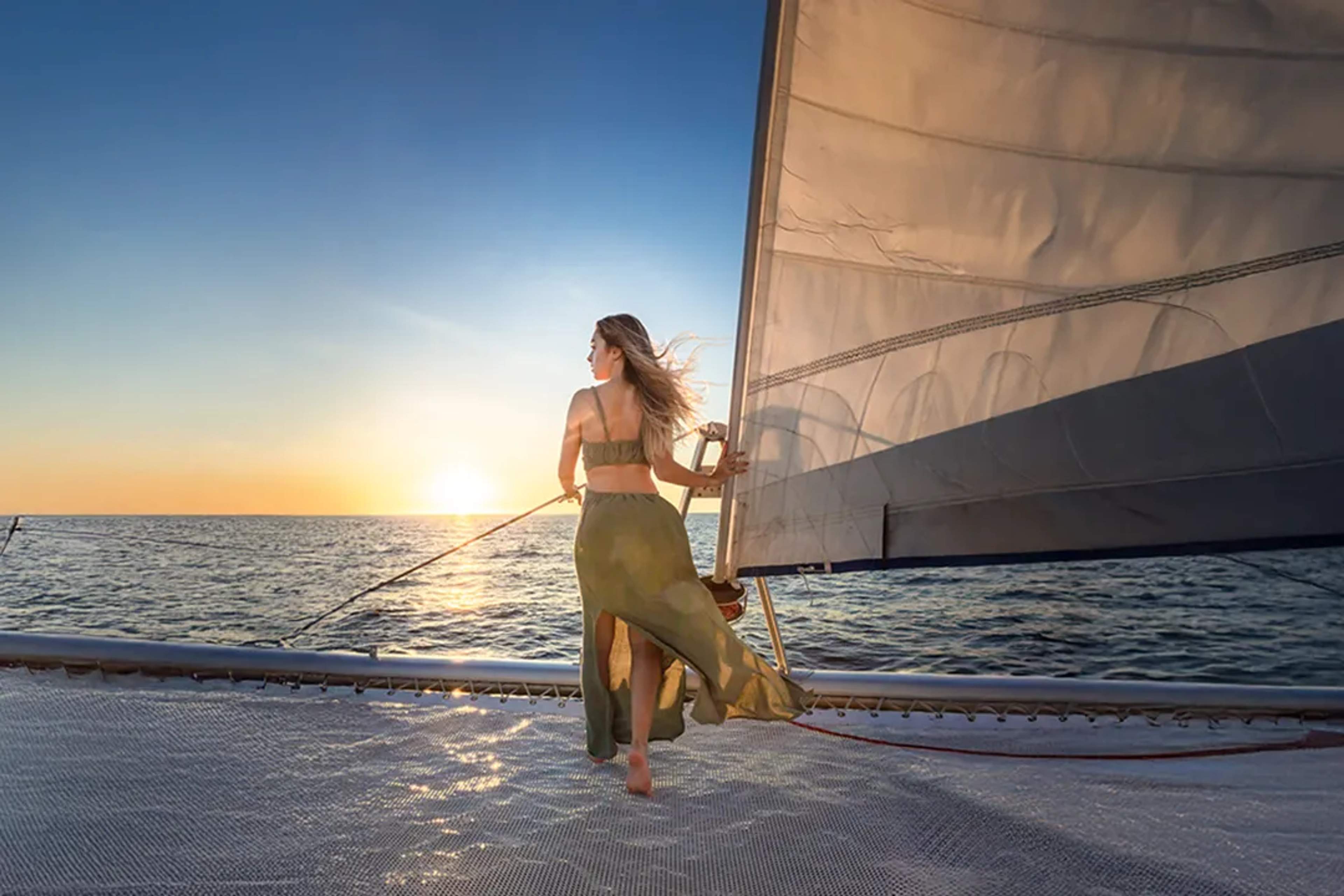 Woman sailing on a catamaran at sunset, enjoying ocean views and a serene luxury experience in Cancun