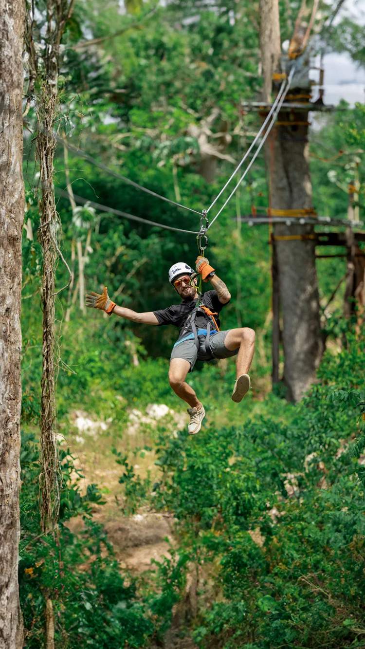 Joven disfrutando una tirolesa en Cancún en un divertido Parque de Aventuras.