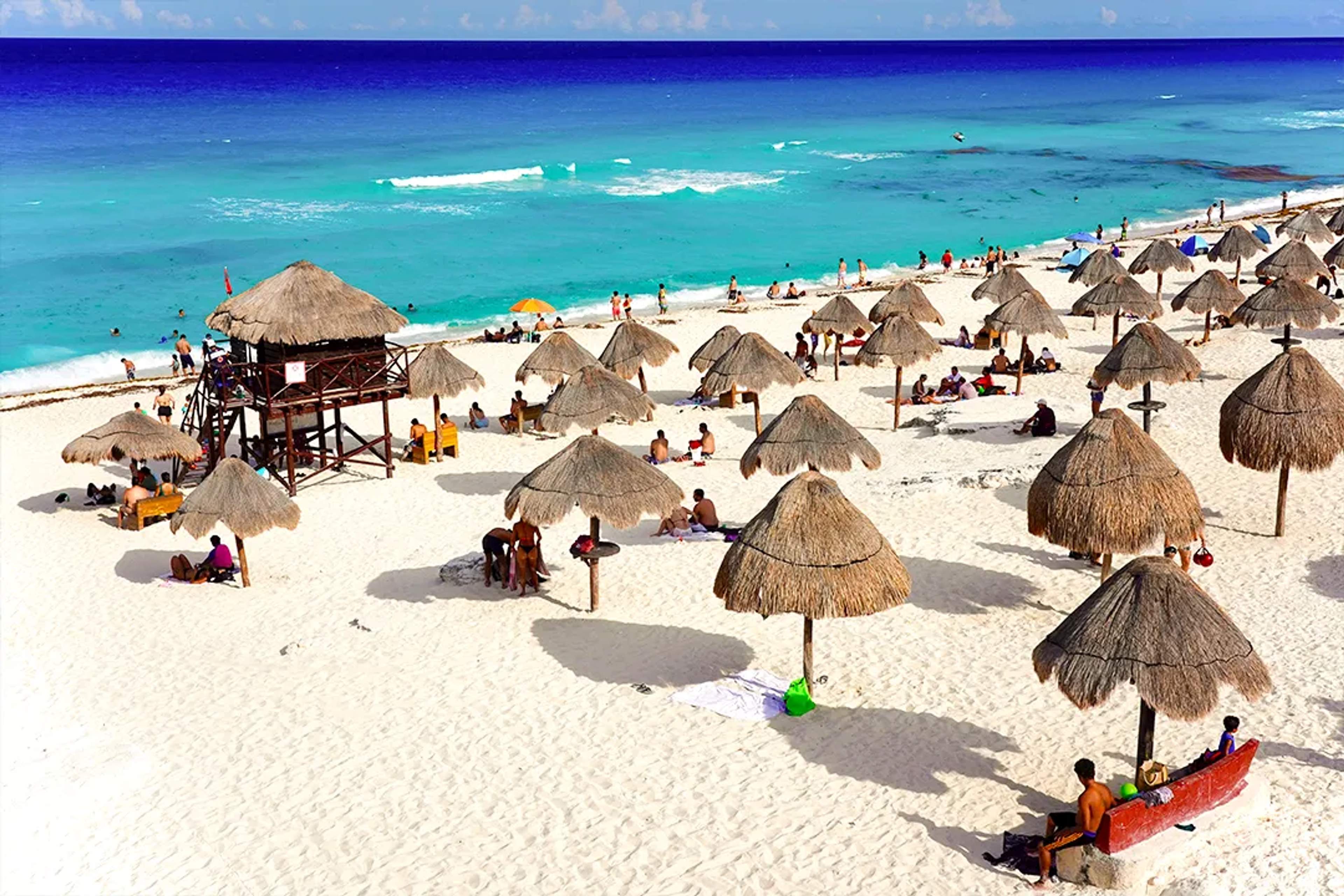 Cancun beach tour with turquoise Caribbean waters white sand palapas and travelers relaxing by the sea