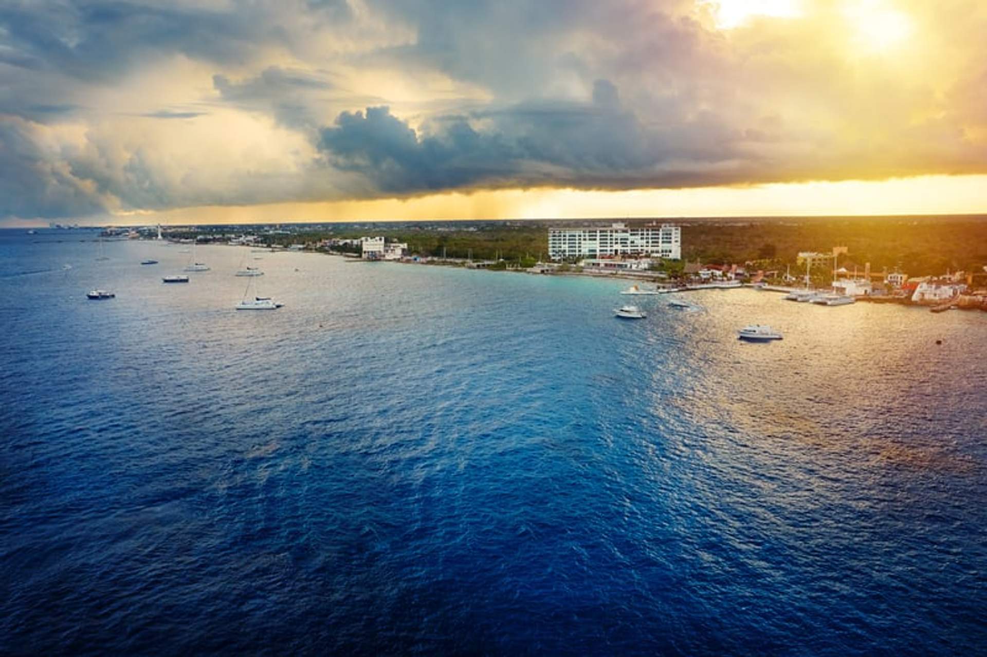 Atardecer en Cancún durante la temporada de huracanes con nubes oscuras y botes en el agua.