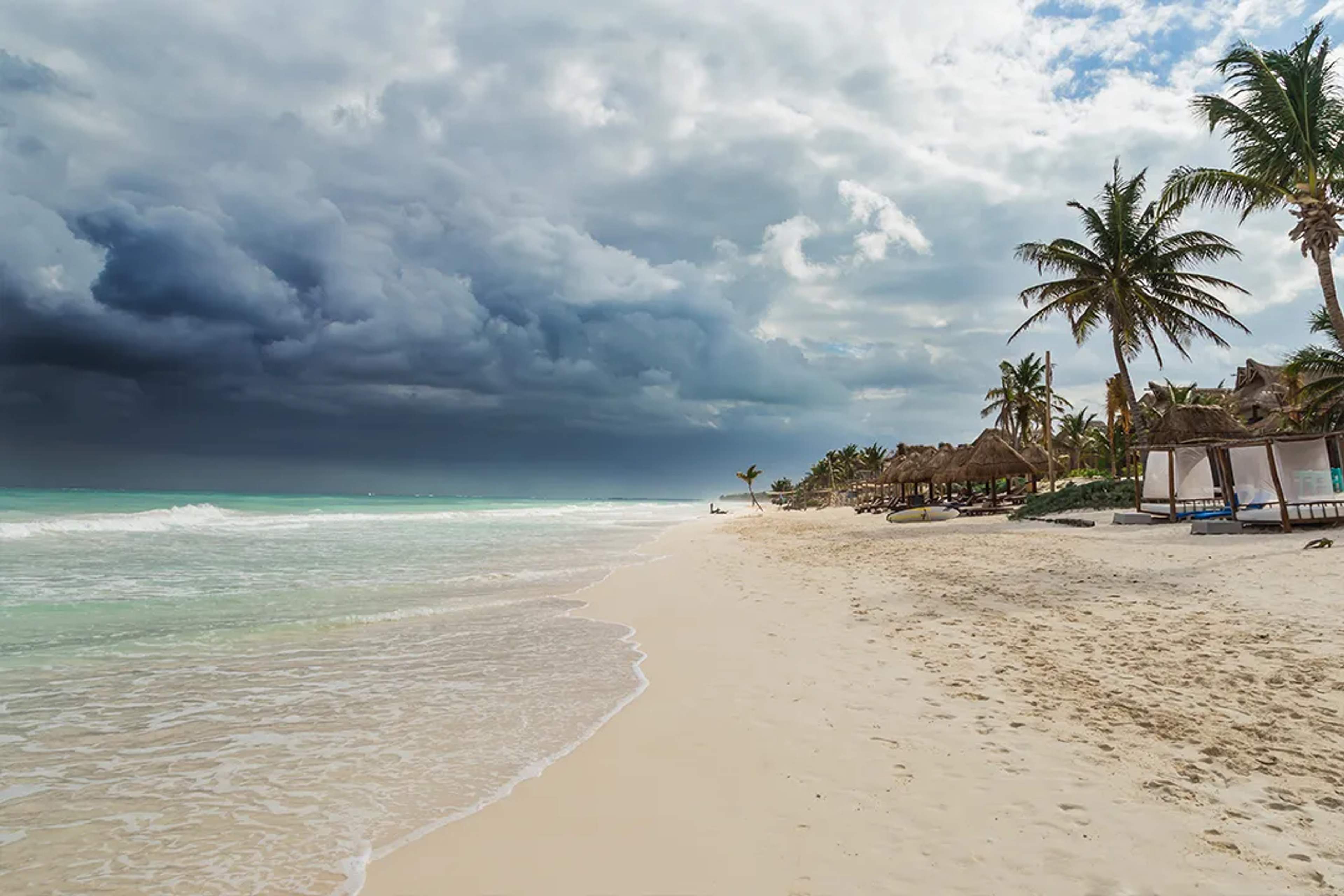 Caribbean beach with palm trees and turquoise water under dramatic clouds in Riviera Maya coastal tour