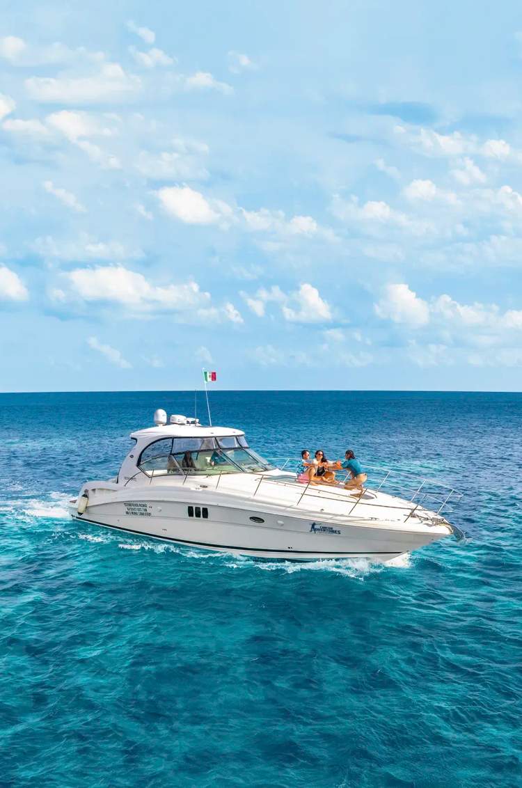 Group of people relaxing and enjoying on the bow of a yacht cruising in turquoise waters.