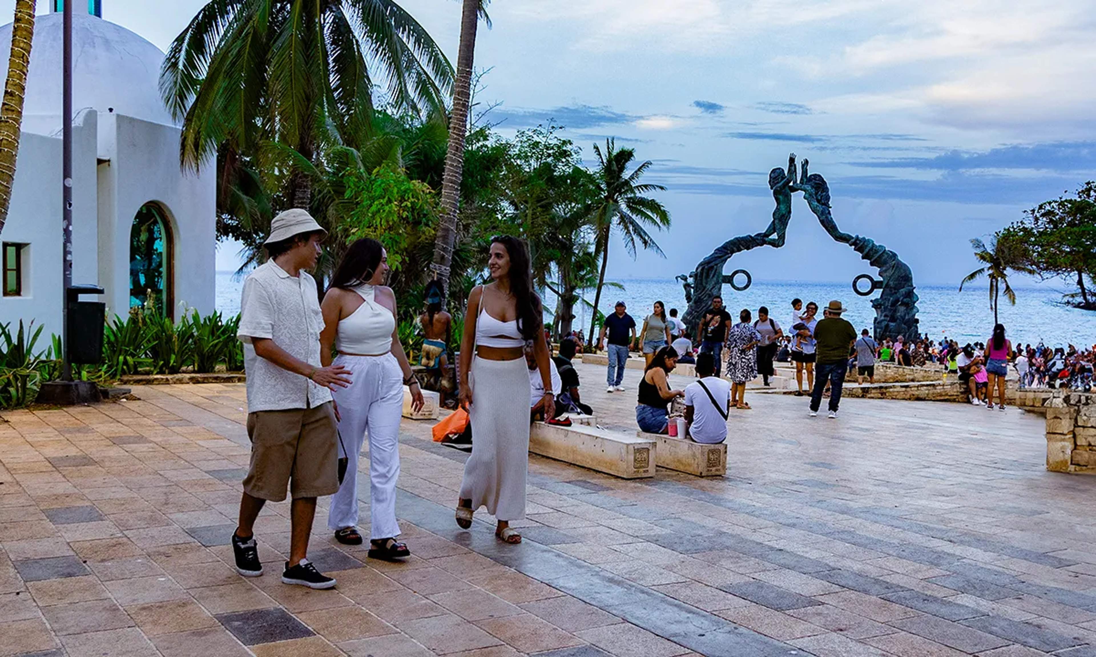 Visitors enjoying a stroll in Playa del Carmen, near the famous beachside sculptures and ocean views.