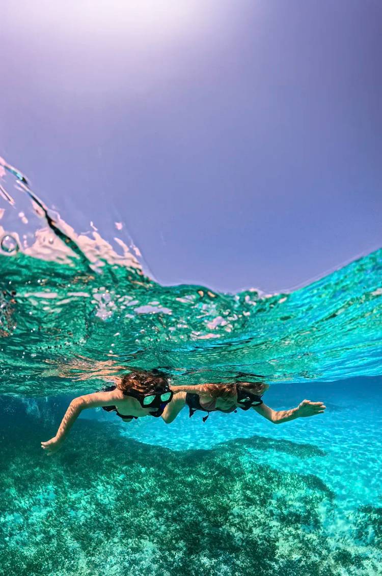 Pareja haciendo snorkel en el caribe como parte de un paseo en yate privado en Cancún.