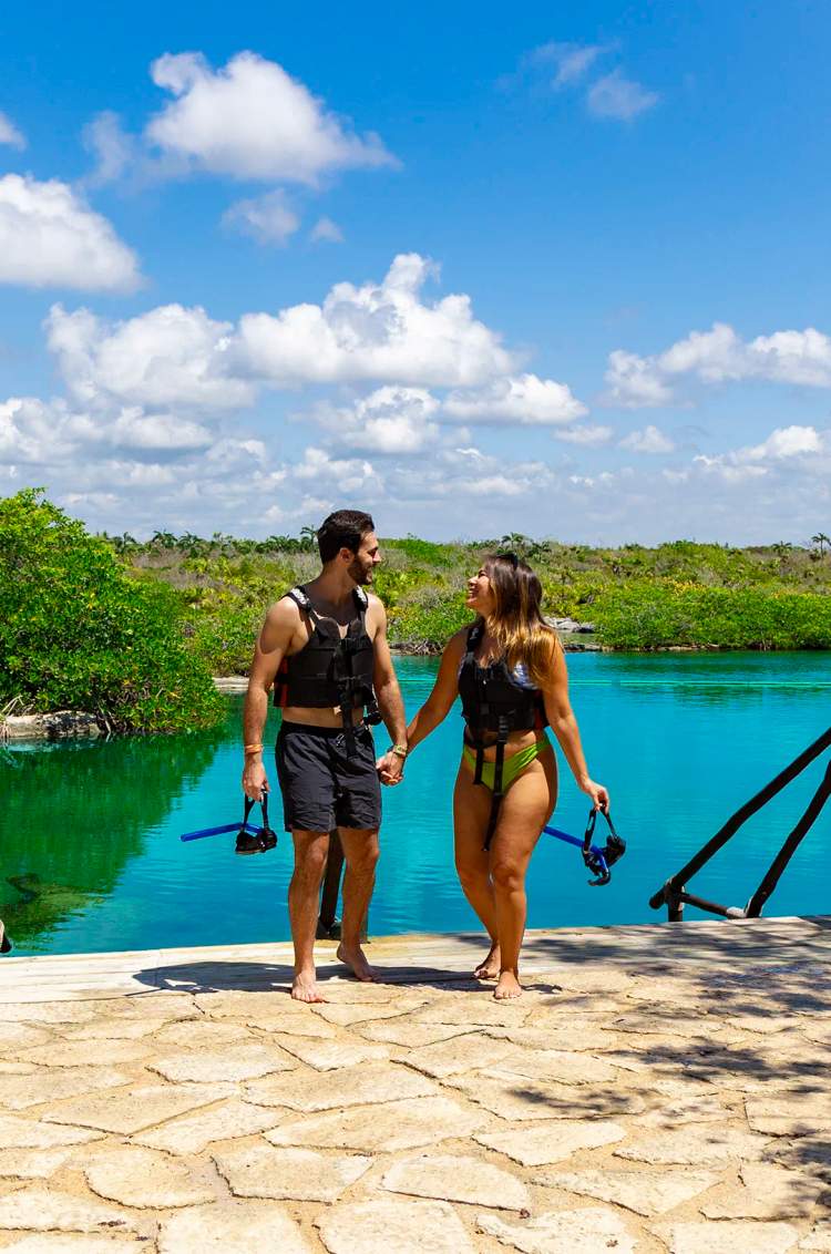 Pareja caminando de la mano junto a un hermoso cenote