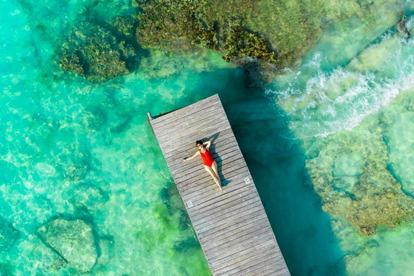 Traveler relaxing on wooden pier above turquoise Caribbean reef during Cancun snorkeling tour adventure