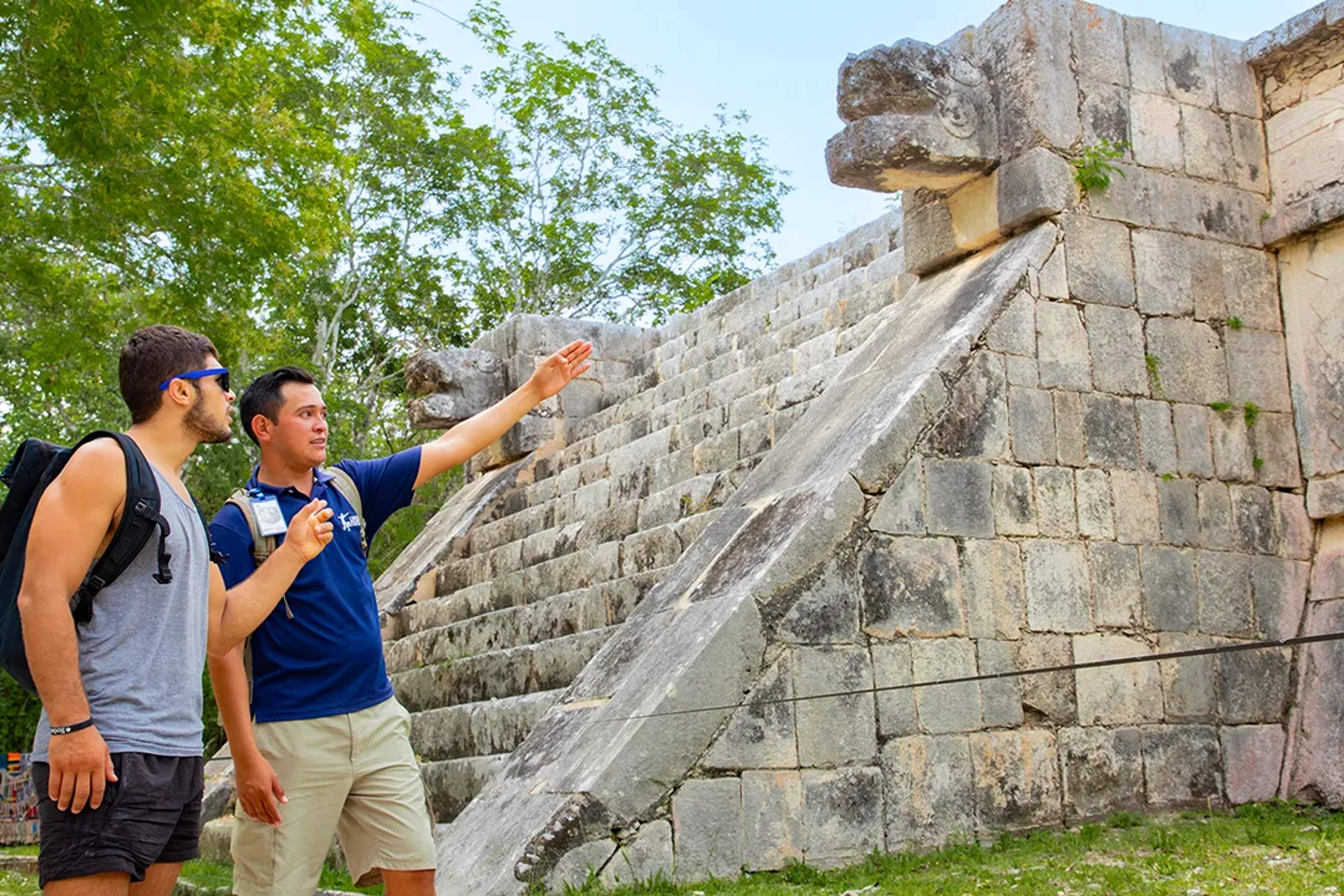 Guide explaining Kukulkan pyramid serpent head at Chichen Itza, Mayan ruins Yucatan guided tour