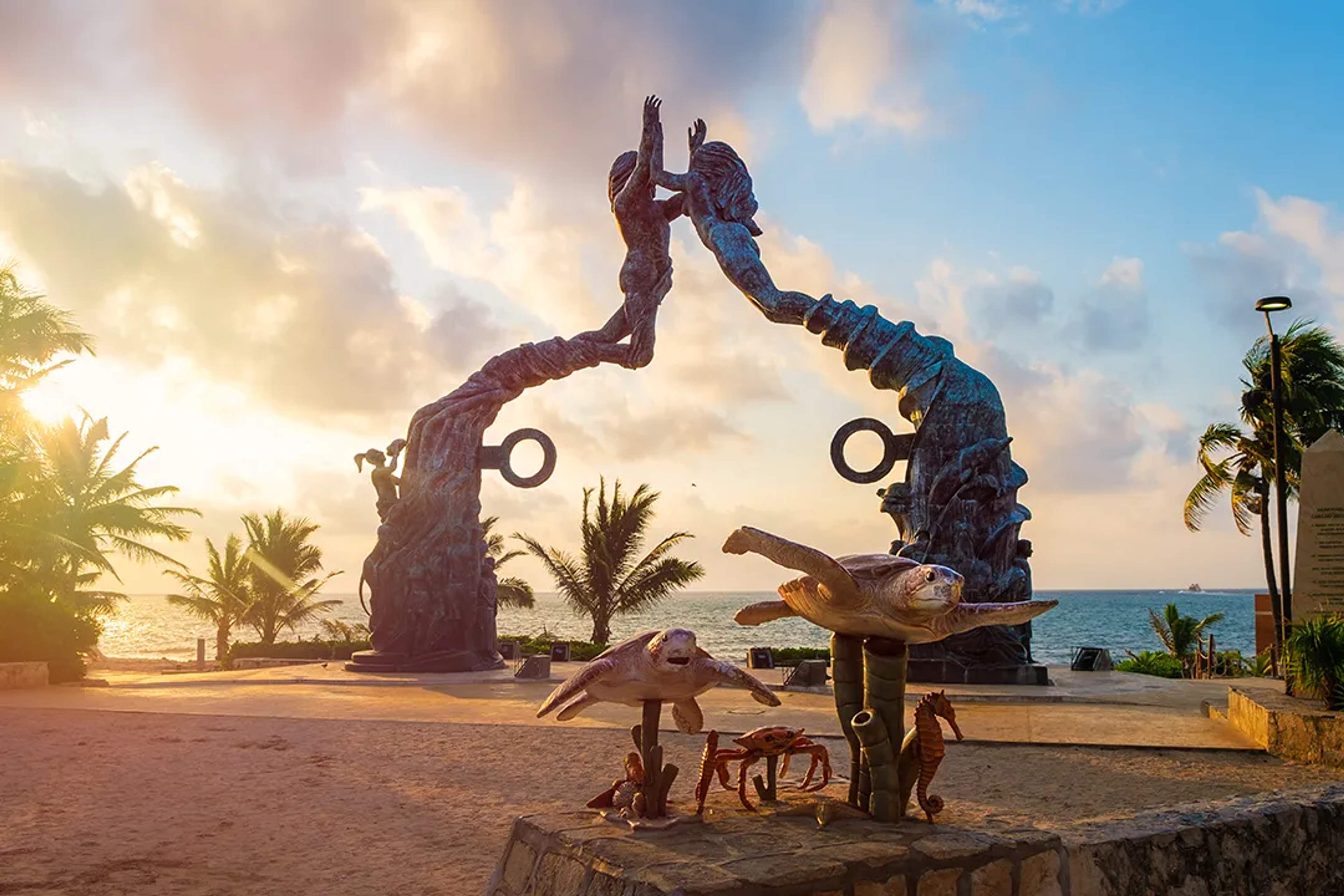 Impresionante escultura en Playa del Carmen con figuras extendidas, adornada con estatuas marinas.