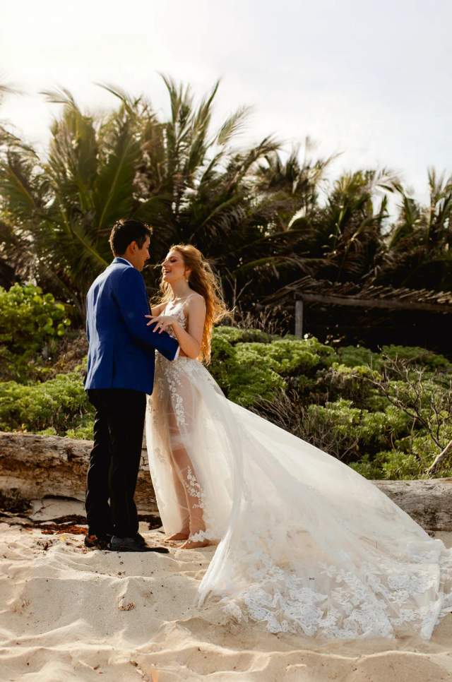 Vista romántica de una pareja en una Boda en la playa en Cancún rodeada por vegetación tropical.