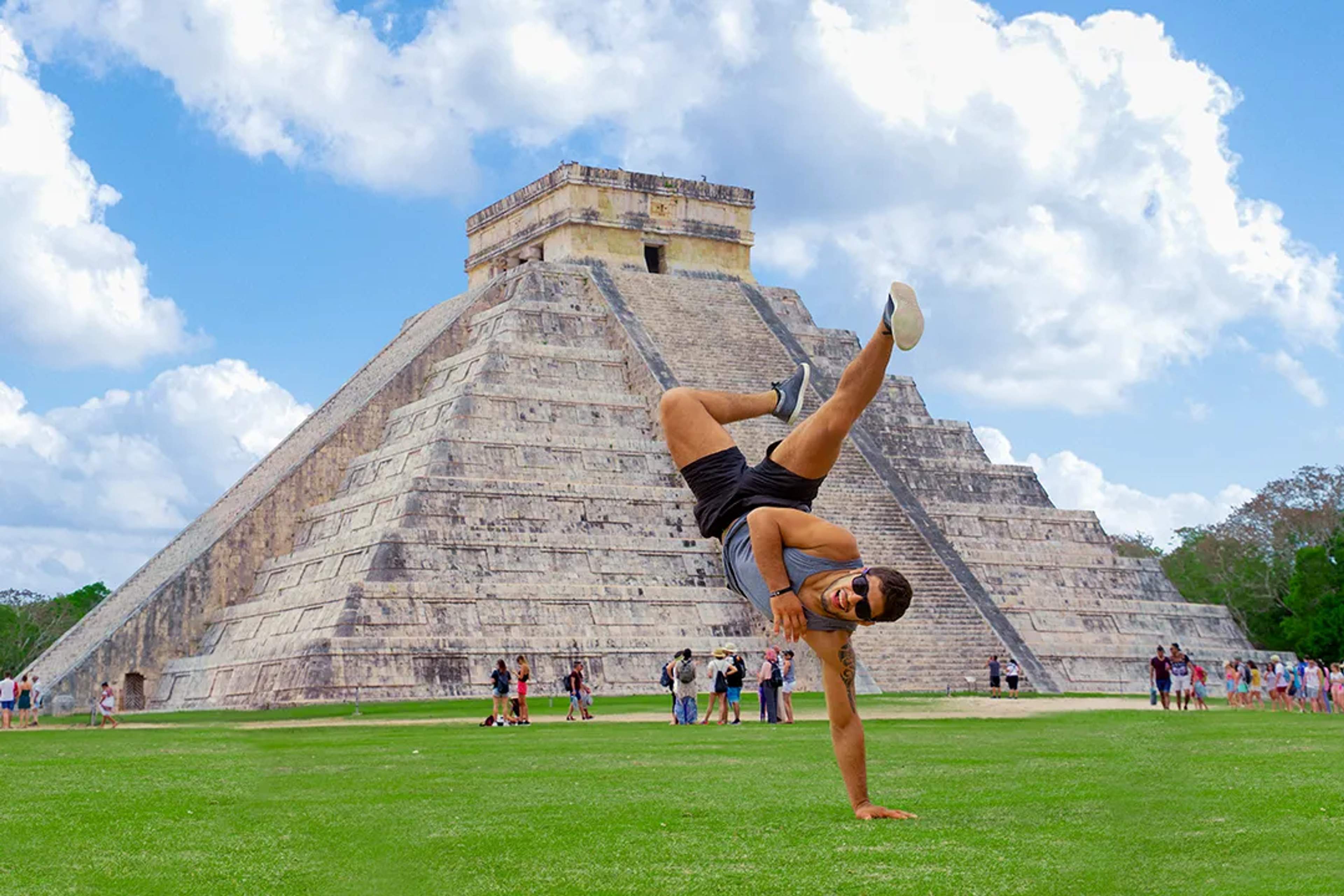 Hombre haciendo una acrobacia frente a la pirámide de Kukulkán en Chichén Itzá, mostrando agilidad.