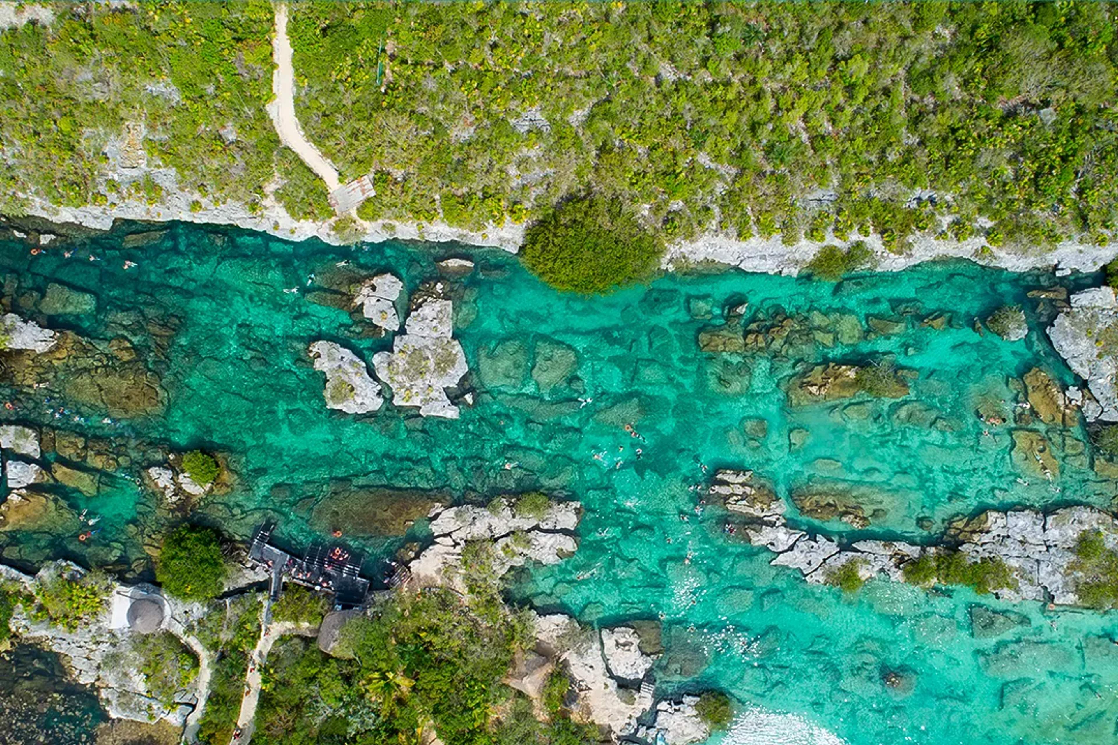 Vista aérea de la laguna Yal Kú, mostrando sus aguas turquesas y la vegetación exuberante que la rodea.
