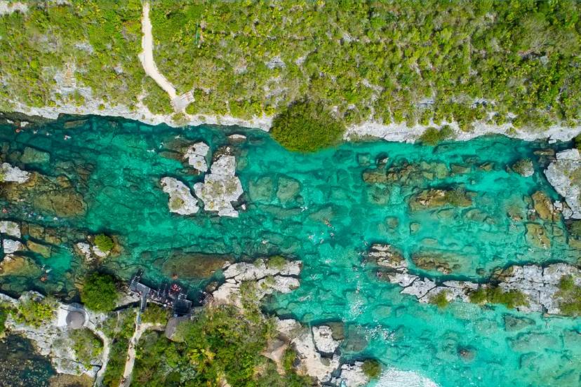 Vista aérea de la laguna Yal Kú, mostrando sus aguas turquesas y la vegetación exuberante que la rodea.