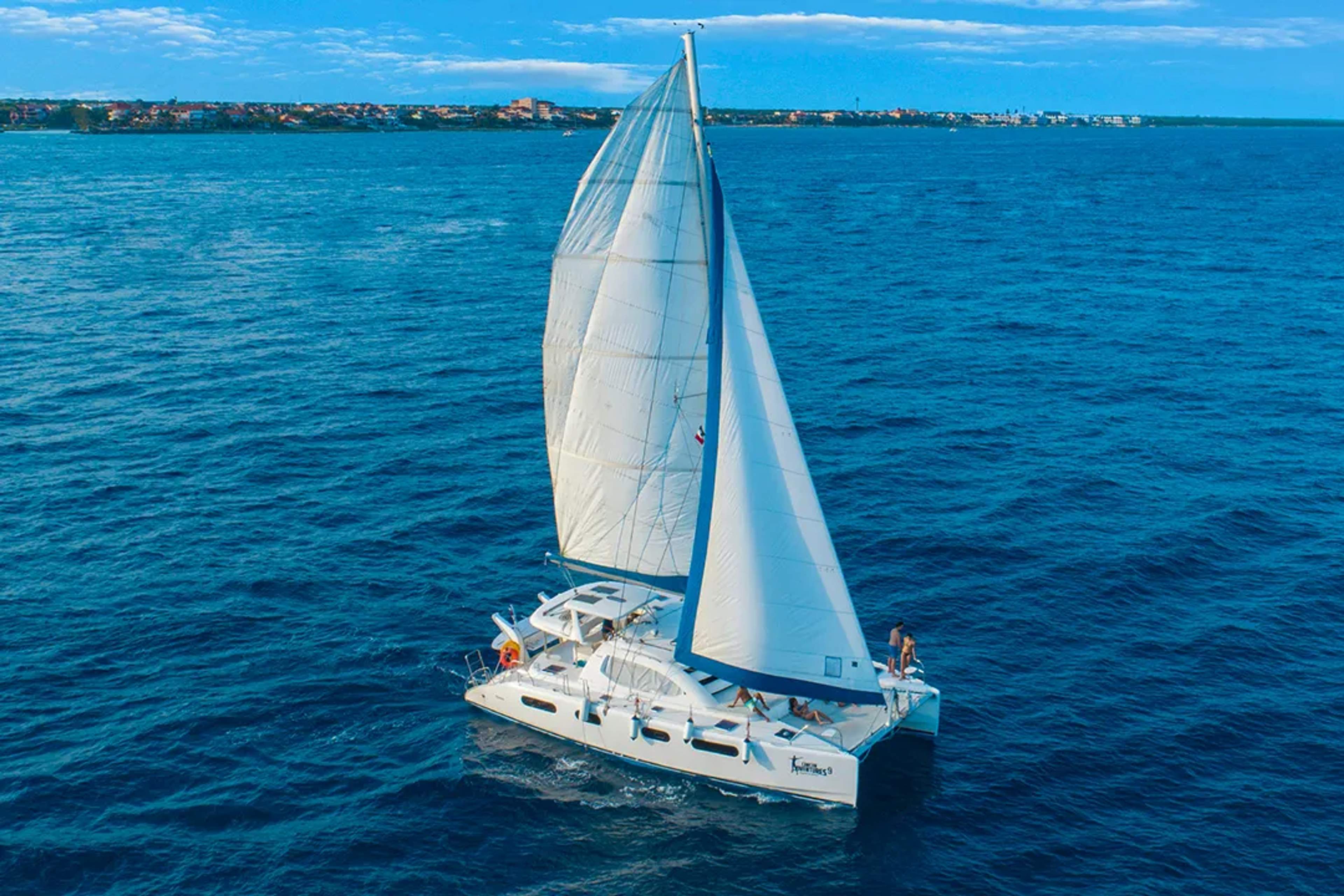 Luxury catamaran sailing on Caribbean Sea, white sails open near coast on guided sailing tour experience