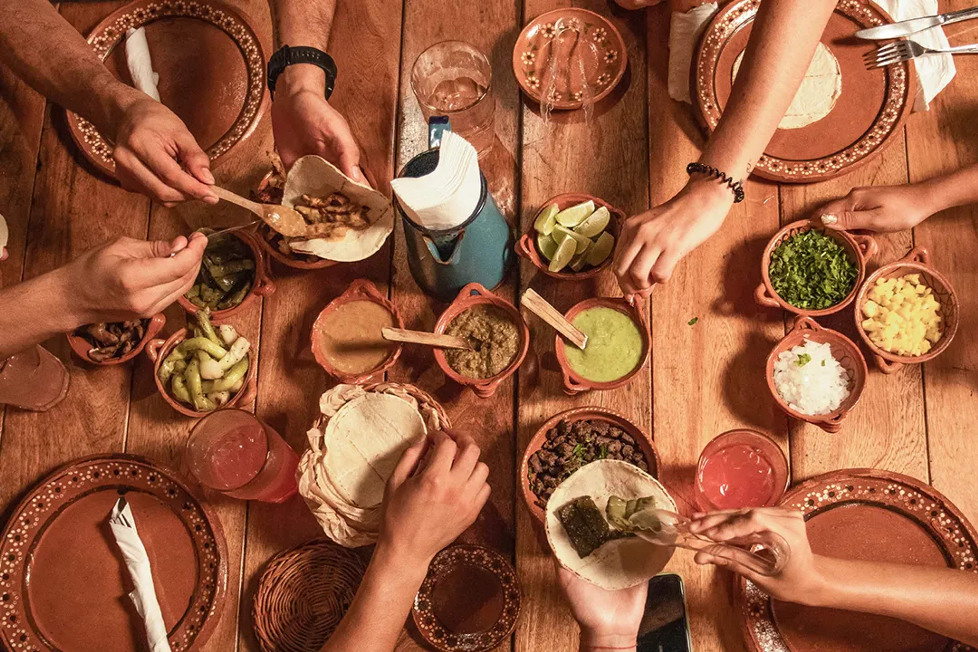 Grupo disfrutando tacos mexicanos tradicionales con tortillas hechas a mano, salsas y ingredientes frescos
