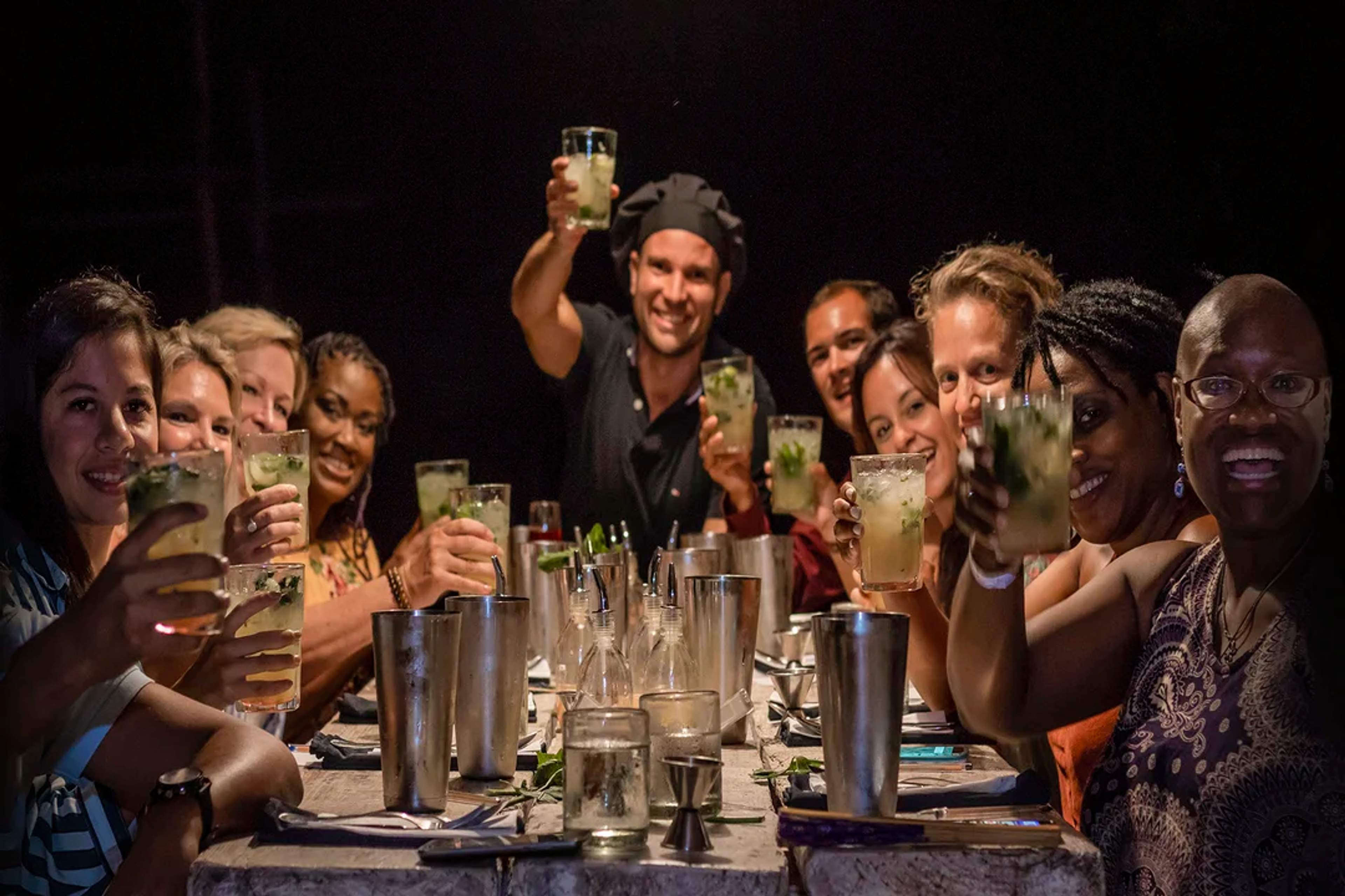 Un grupo alegre brinda con sus bebidas en una animada cena, celebrando juntos.