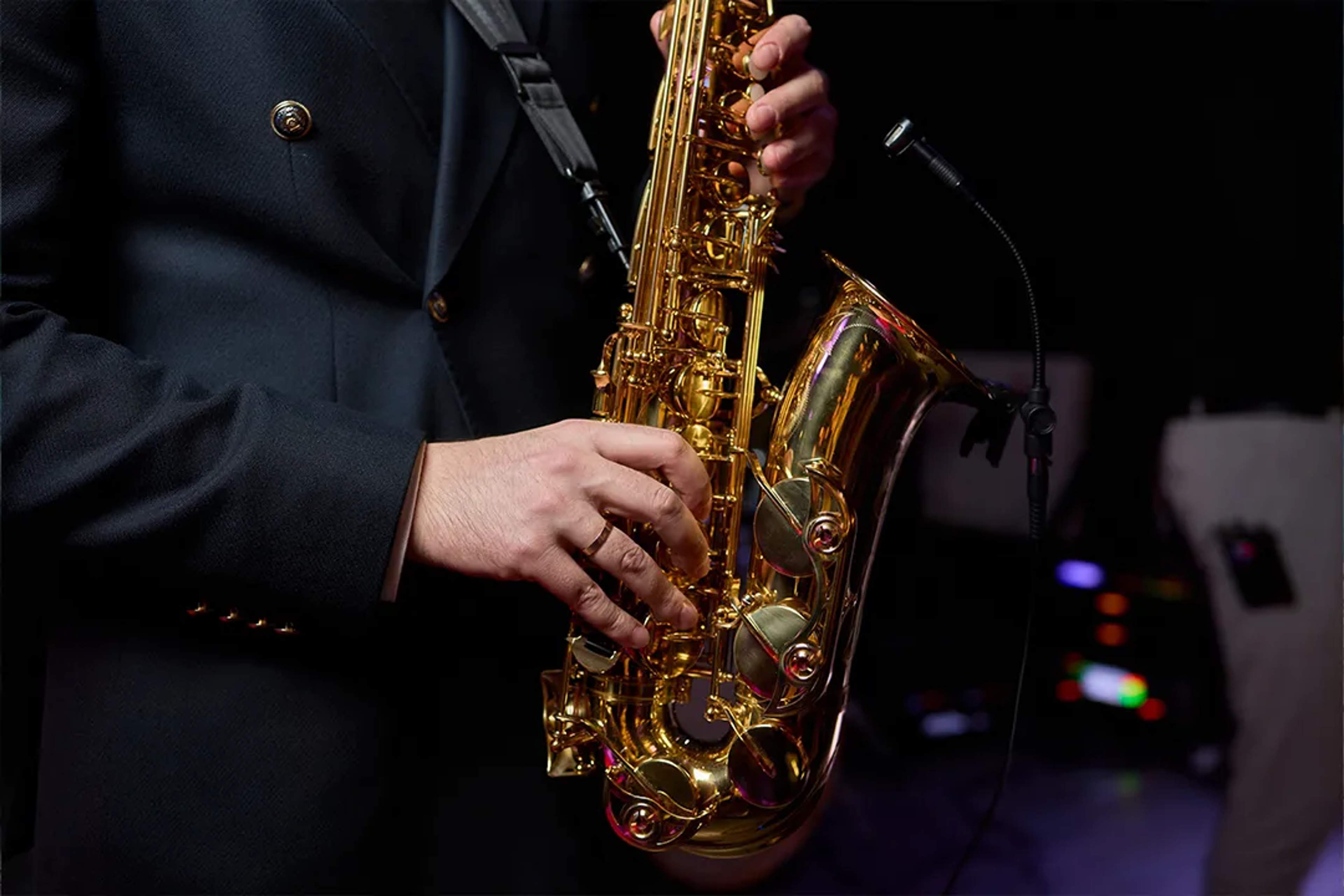Primer plano de un músico tocando un saxofón dorado durante una presentación en vivo.