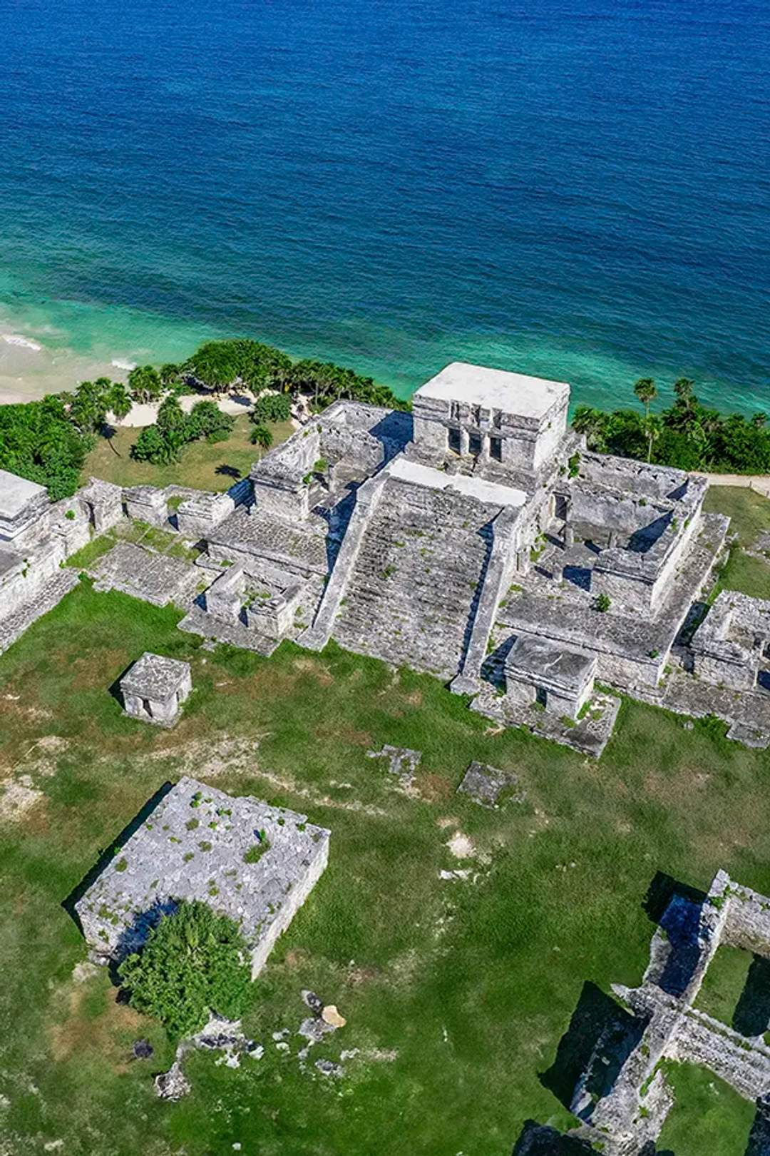 Aerial view of the ancient Mayan ruins of Tulum perched on a cliff overlooking the Caribbean Sea.