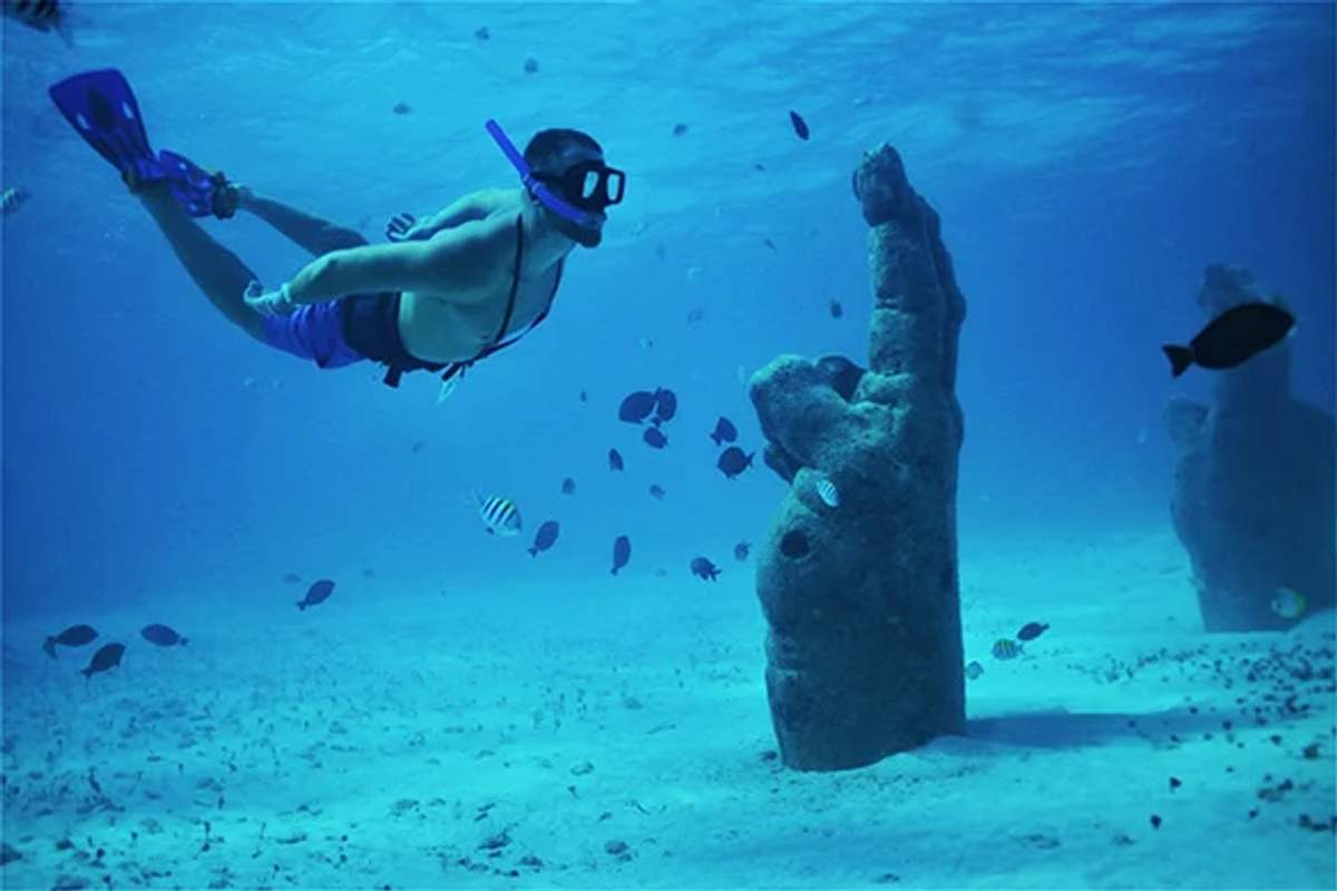 Un snorkeler explorando esculturas submarinas rodeadas de peces en el MUSA, el Museo Subacuático de Cancún.