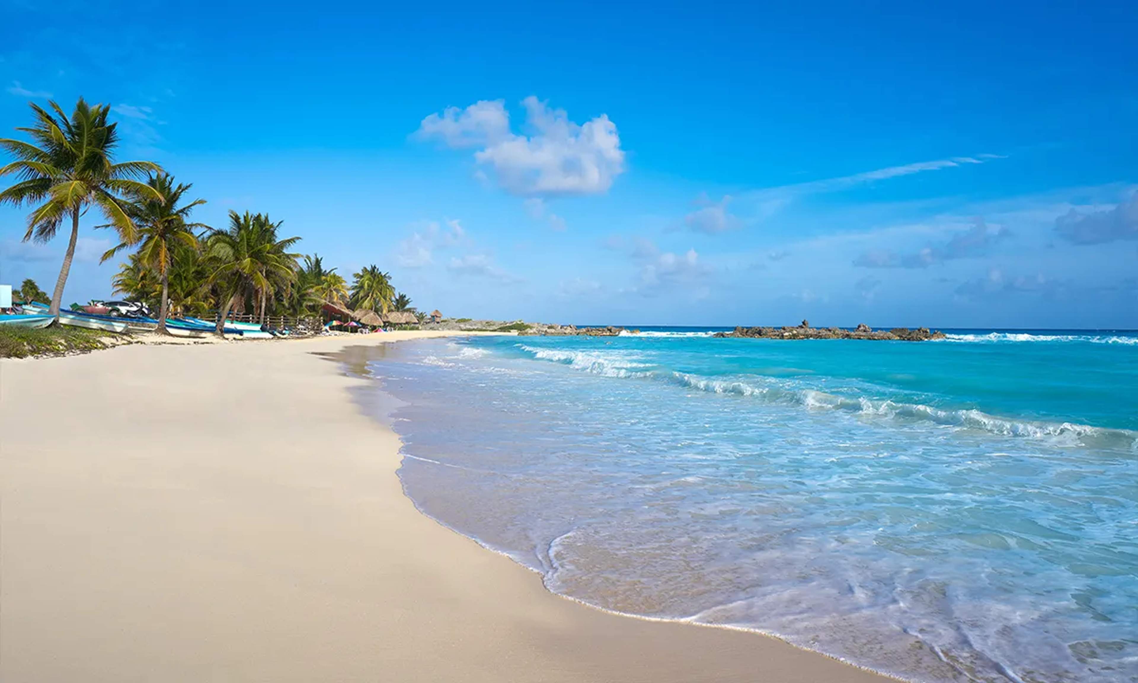 Playa de arena blanca en Cozumel, rodeada de palmeras y aguas cristalinas, un paraíso tropical ideal para relajarse.