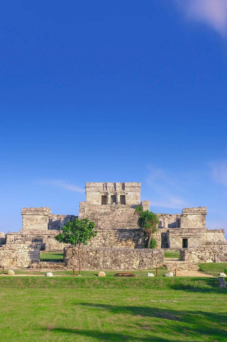 Las antiguas ruinas de Tulum se alzan frente al mar Caribe, bajo un cielo azul despejado.