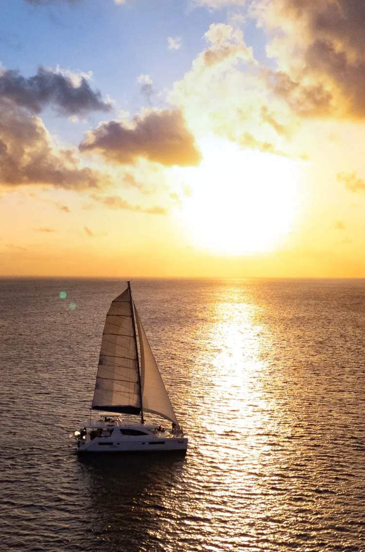Un velero deslizándose en el océano durante una impresionante puesta de sol, capturando la serena belleza del momento.