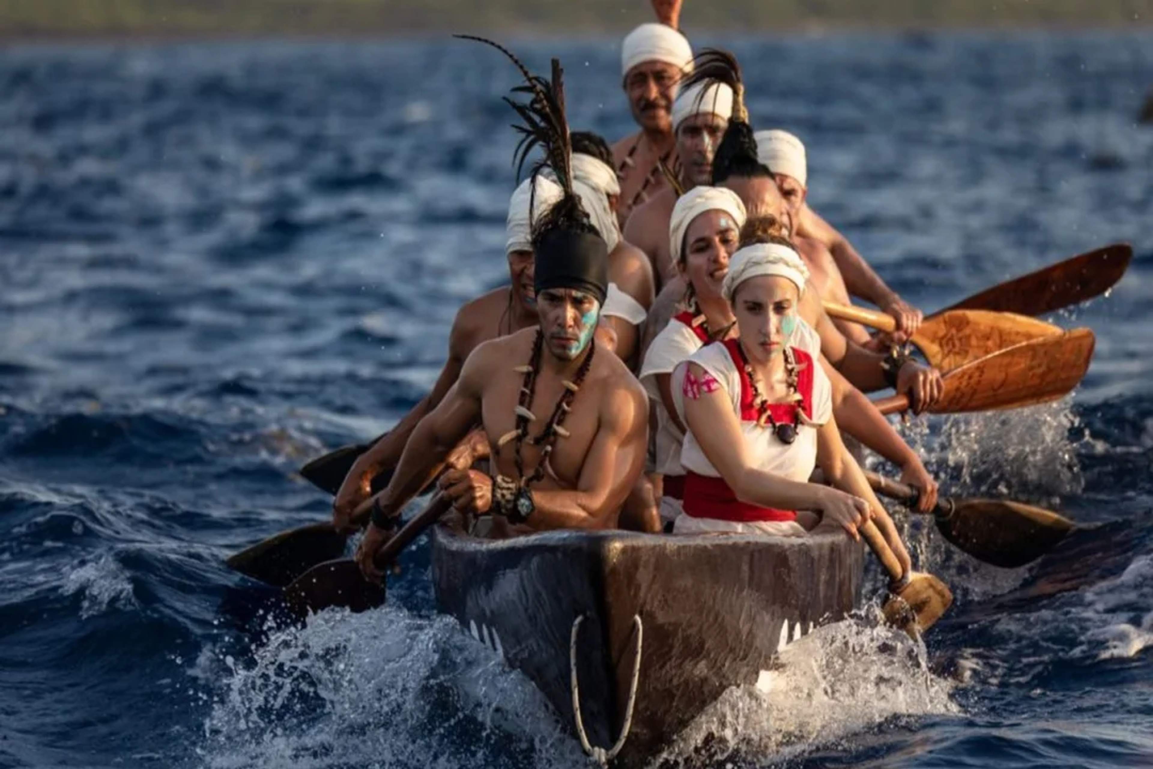 Recreación maya de travesía en canoa, con remeros vestidos con trajes tradicionales en el mar.