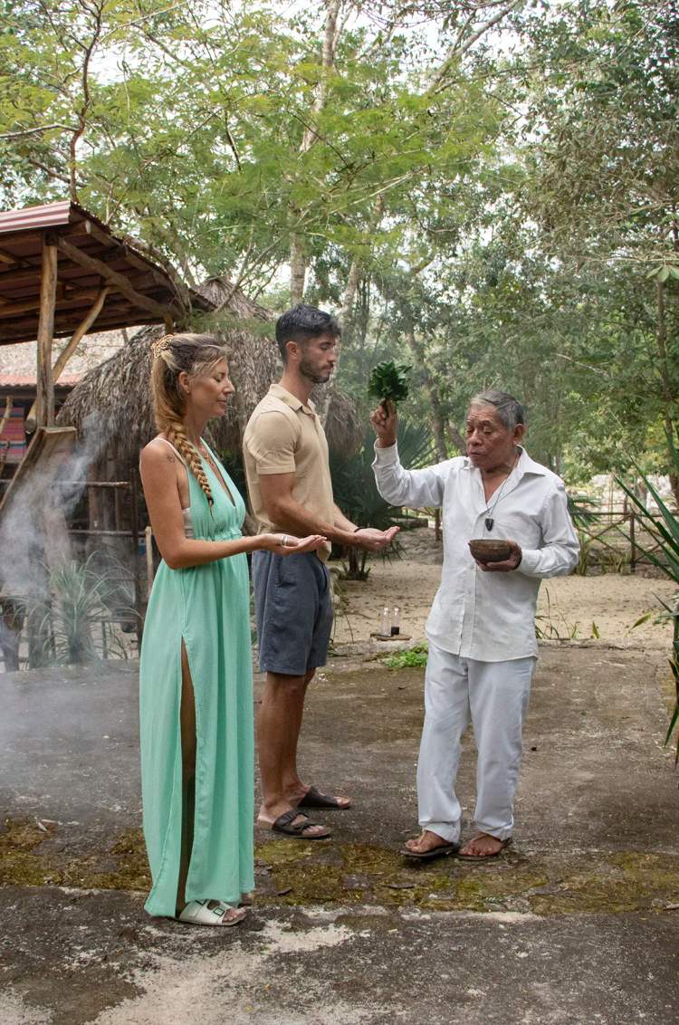 A Mayan shaman performs a purification ritual for a couple, surrounded by nature and sacred smoke.