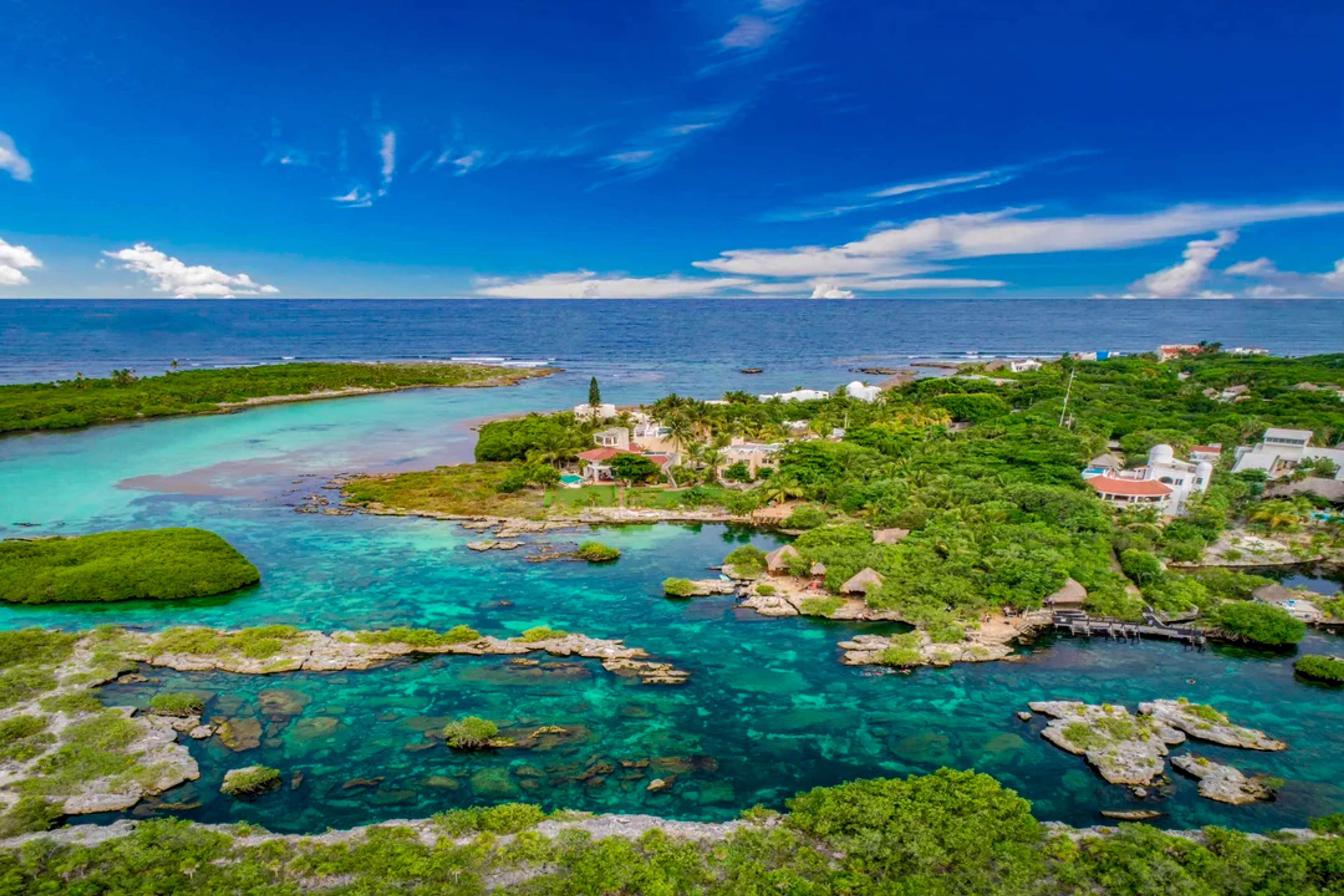Aerial view of a tropical coastal paradise with turquoise waters, lush greenery, and coral reefs.