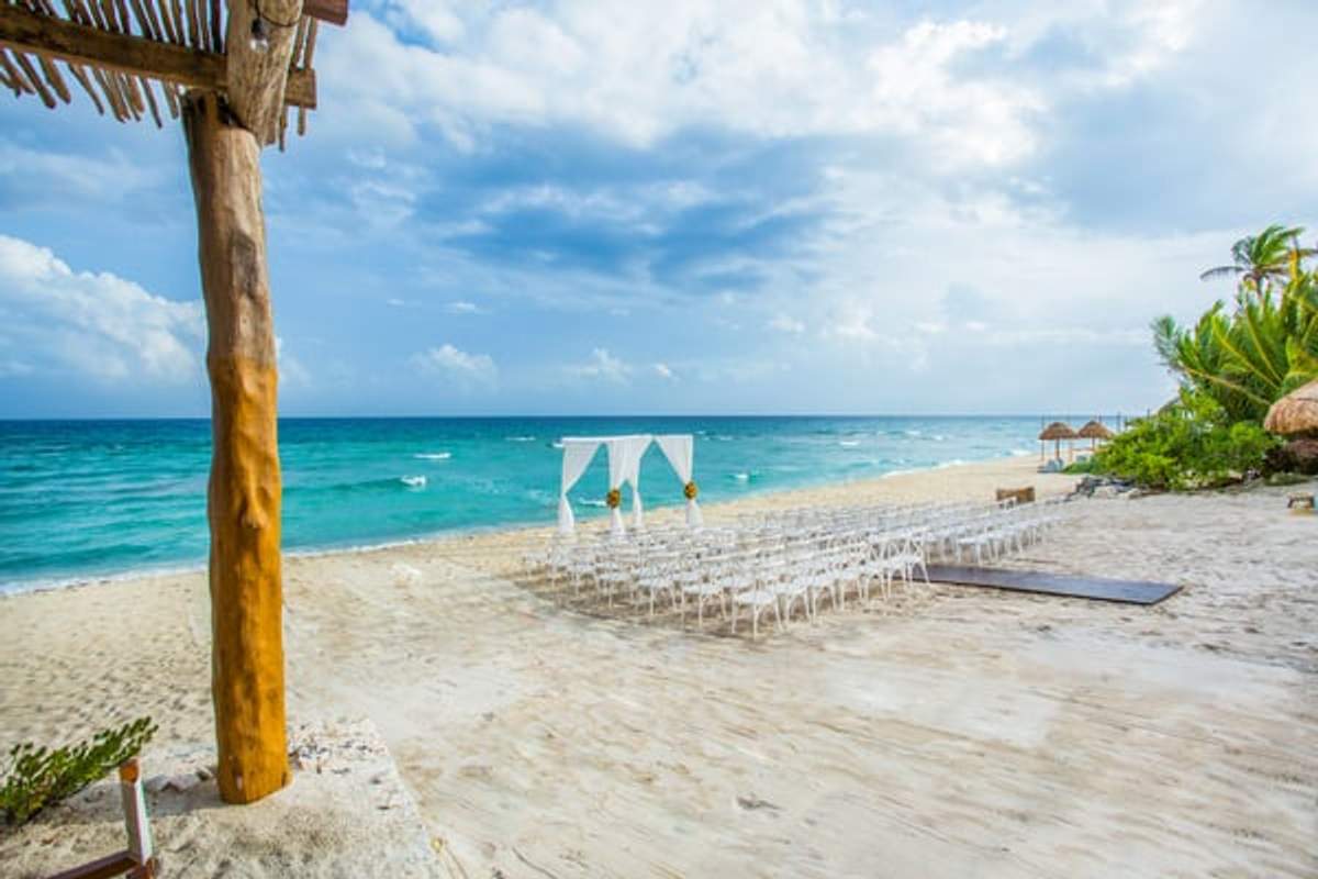 Wedding reception setup on the beach at Punta Venado, Cancun, with chairs and a white arch.