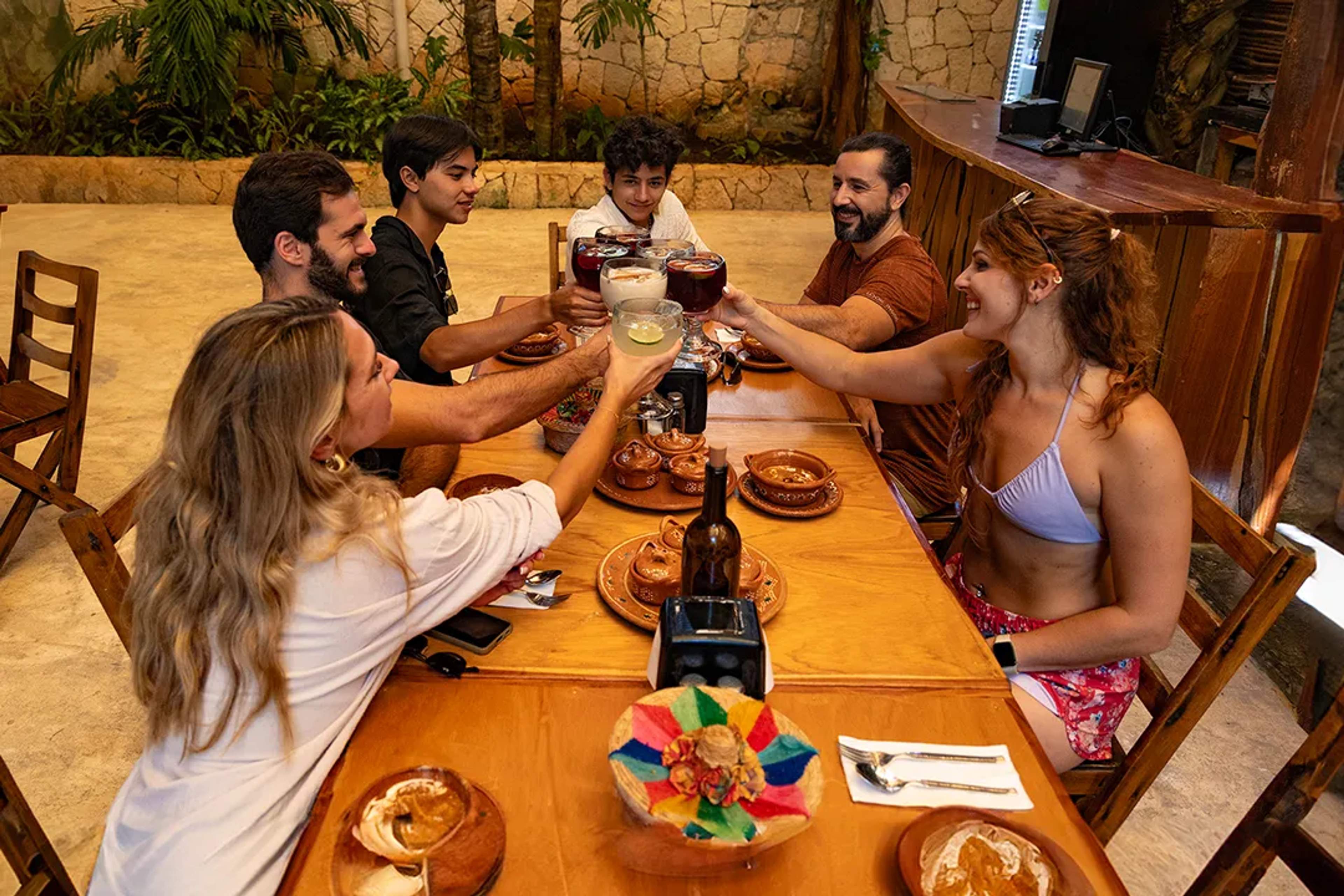 Group of friends toasting at a Mexican restaurant, enjoying food and good company.