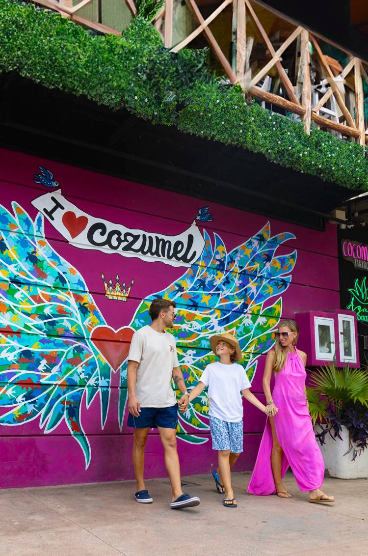 Family walking in front of a colorful mural that says "I ♥ Cozumel."
