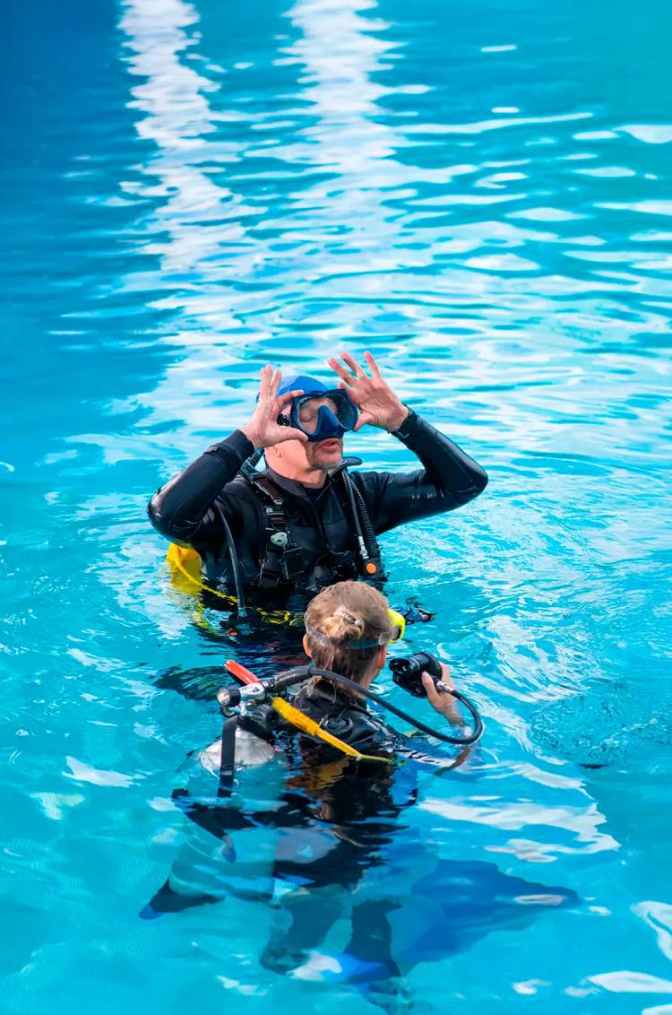 PADI instructor teaching how to place her scuba diving mask during a Discover Scuba Lesson in Cancun.