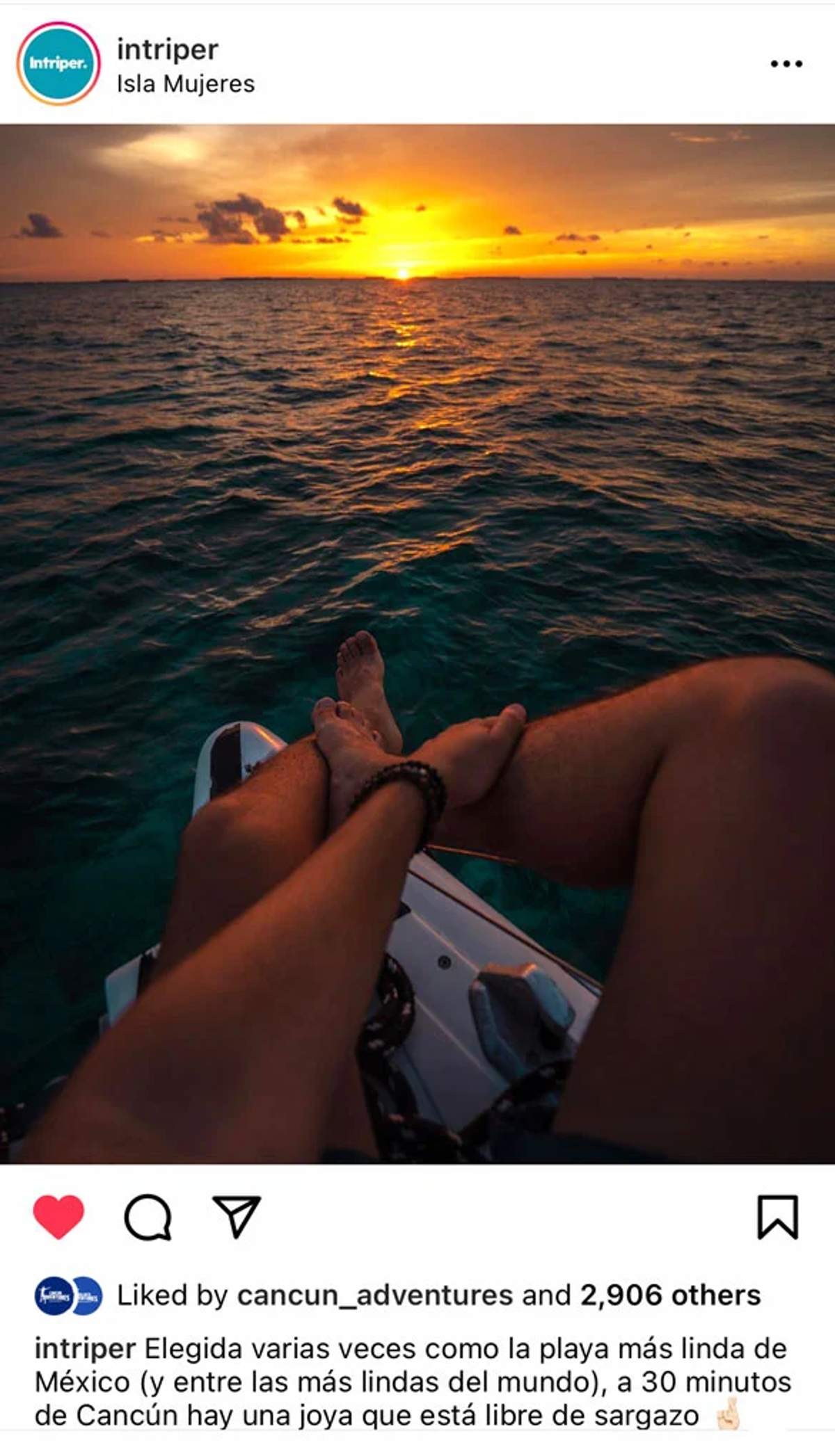 Una persona se relaja en un barco con las piernas estiradas hacia la puesta de sol sobre el océano, capturando los colores vibrantes del cielo y el agua en Isla Mujeres.