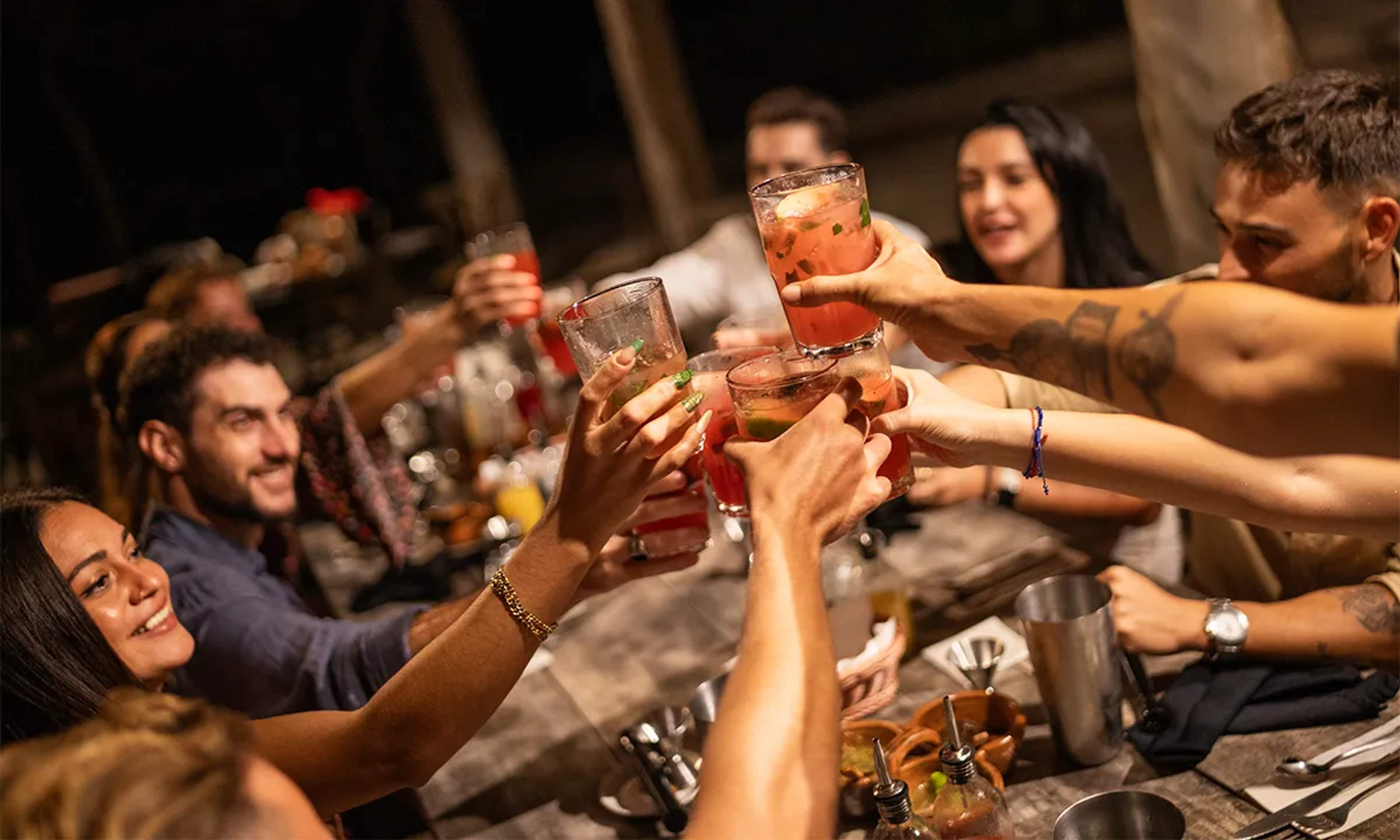 A lively group toasting with drinks, enjoying Cancun's vibrant nightlife and social experiences.