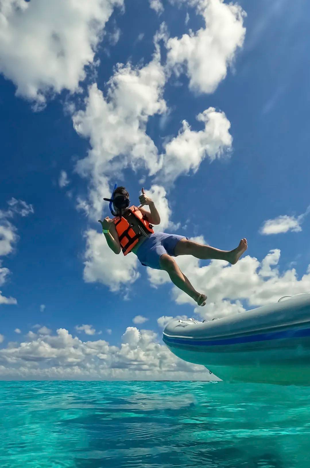 Snorkel en El Cielo, Cozumel: Hombre saltando de un bote al agua cristalina con equipo de snorkel.